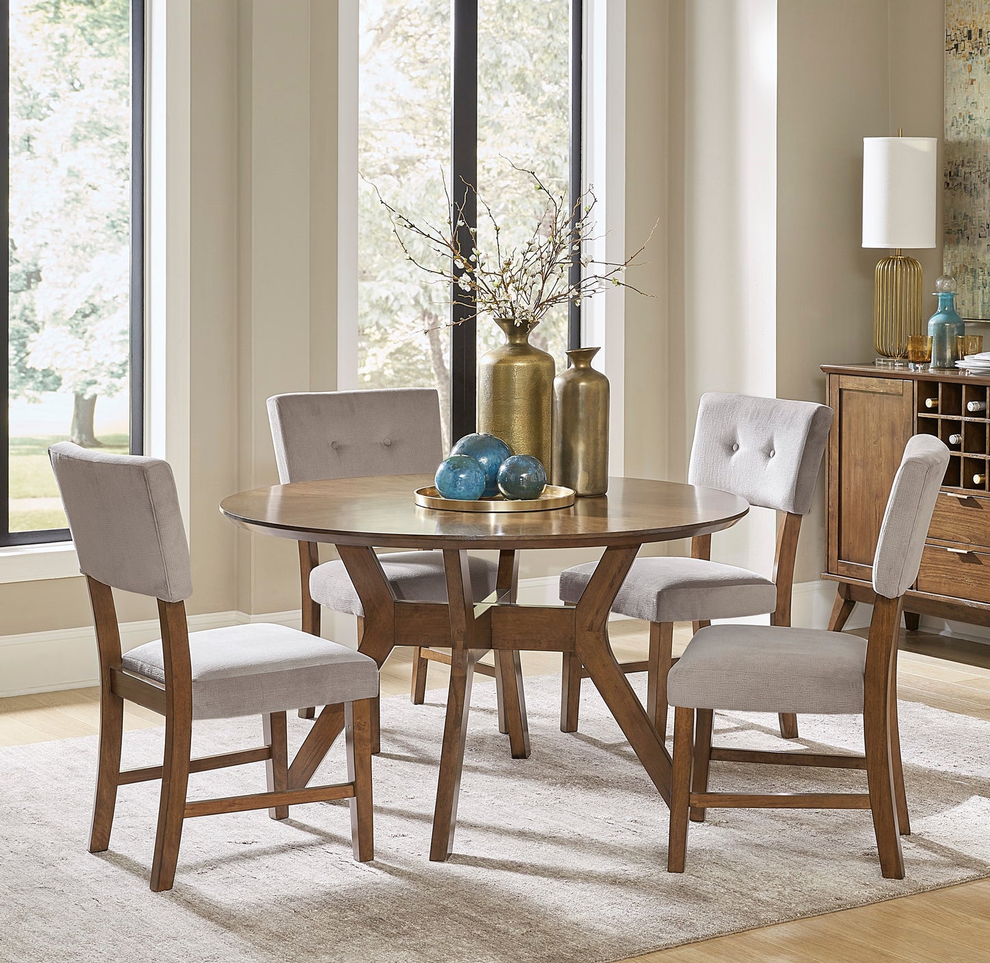 Round oak dining table with four grey upholstered chairs and wood base