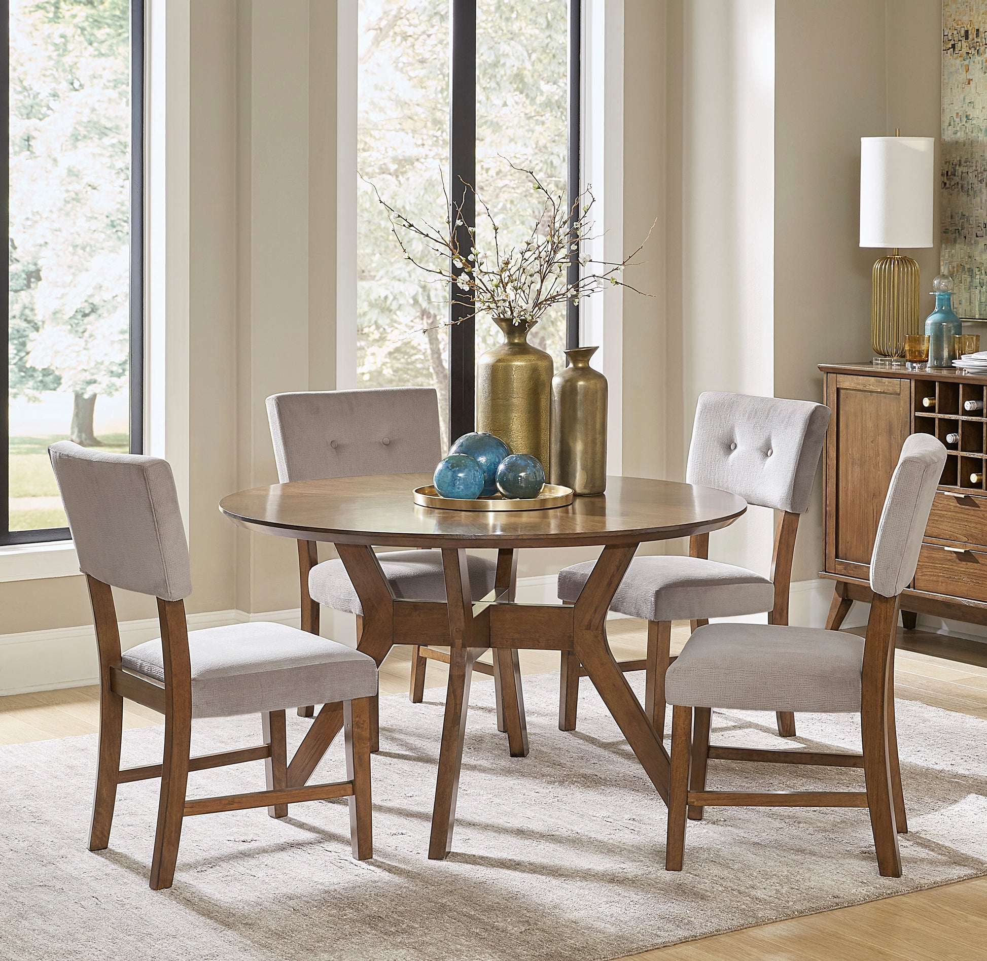 Round oak dining table with four grey upholstered chairs and wood base