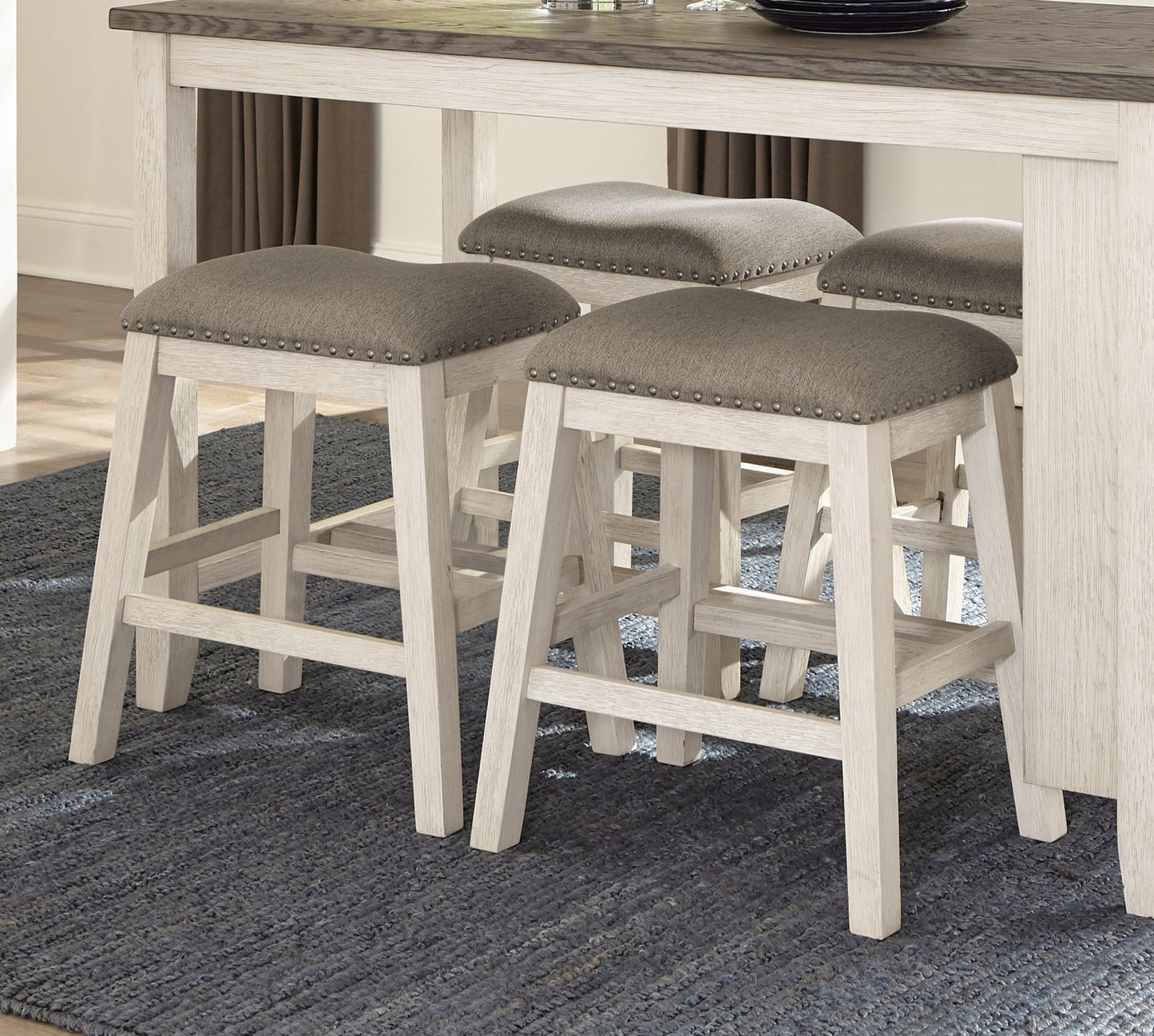 Gray upholstered counter stools with nailhead trim and distressed wood legs