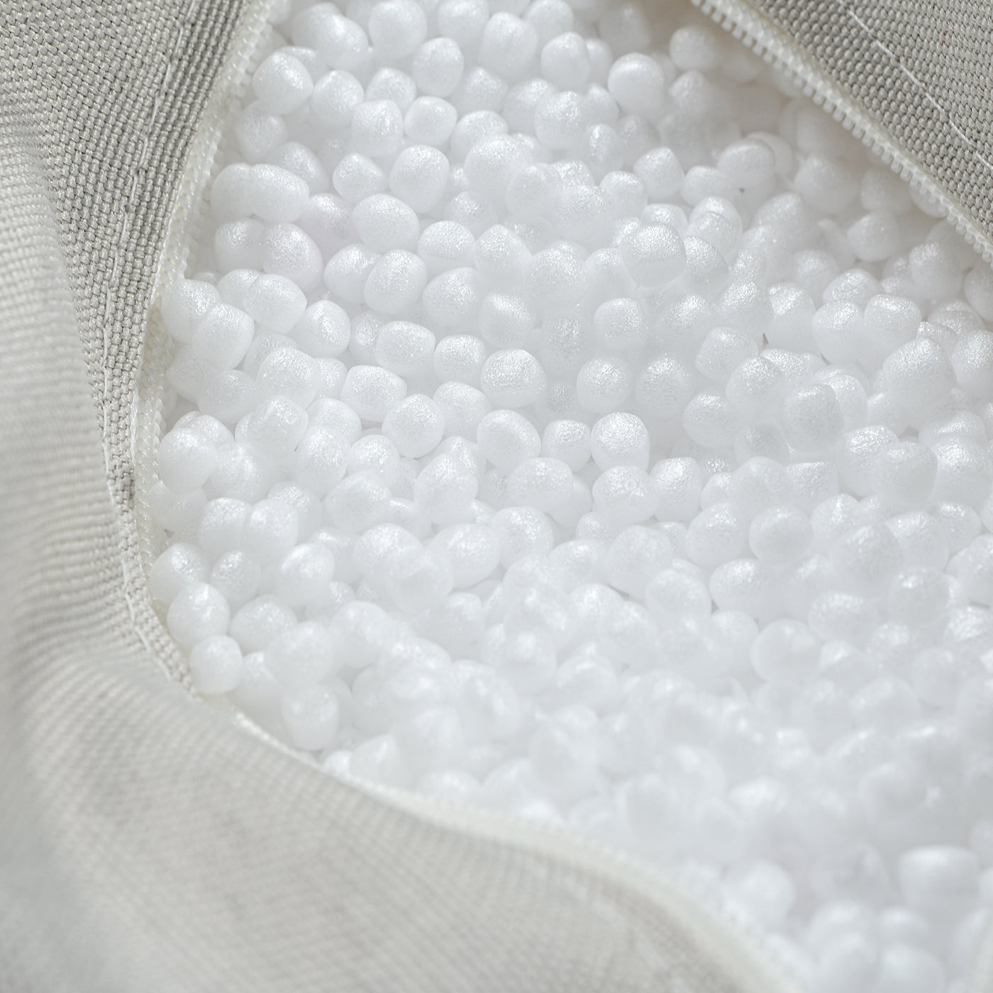 Closeup of white EPS bead filling inside a gray fabric bean bag chair