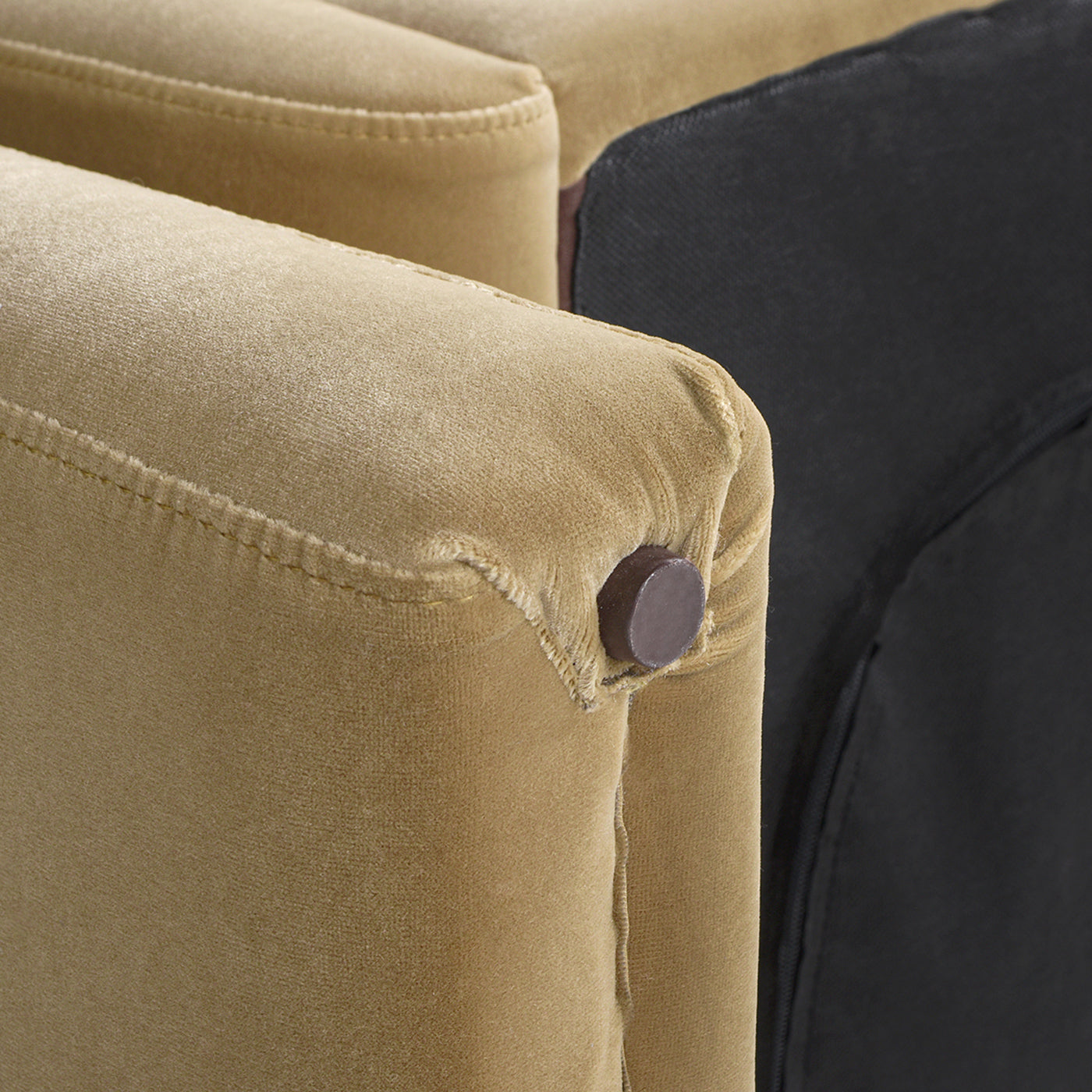 Closeup of a tan velvet armchairs tufted armrest with dark brown button detail