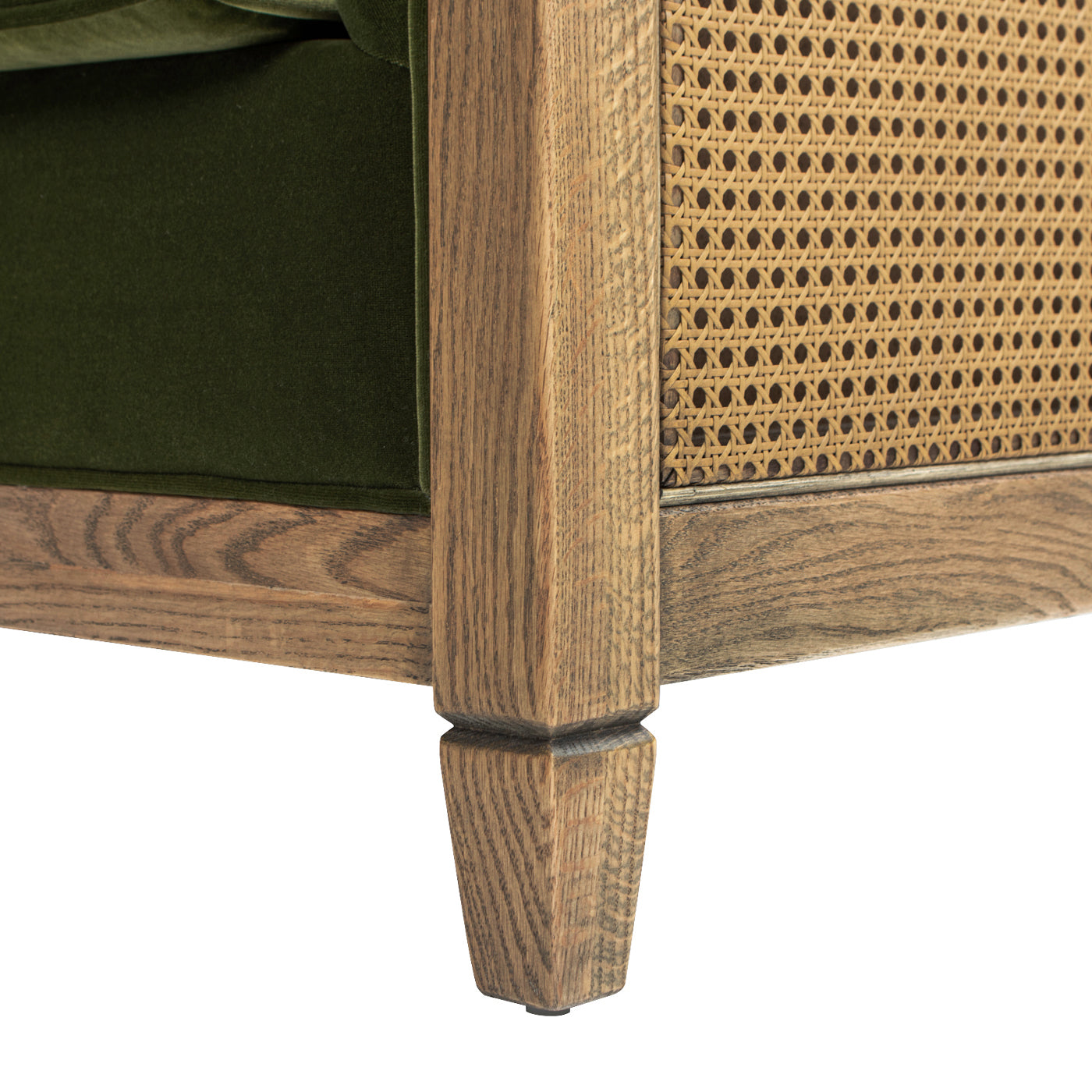 Closeup of green velvet armchair leg with natural wood cane detailing