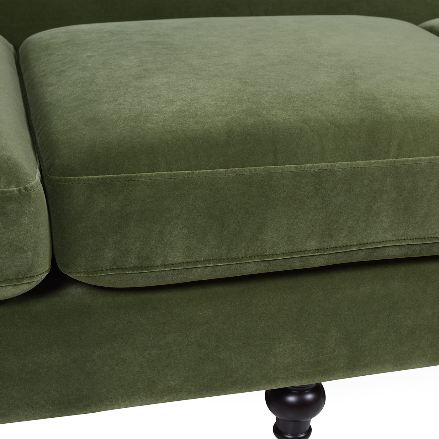 Closeup of plush moss green velvet sofa upholstery with tailored stitching