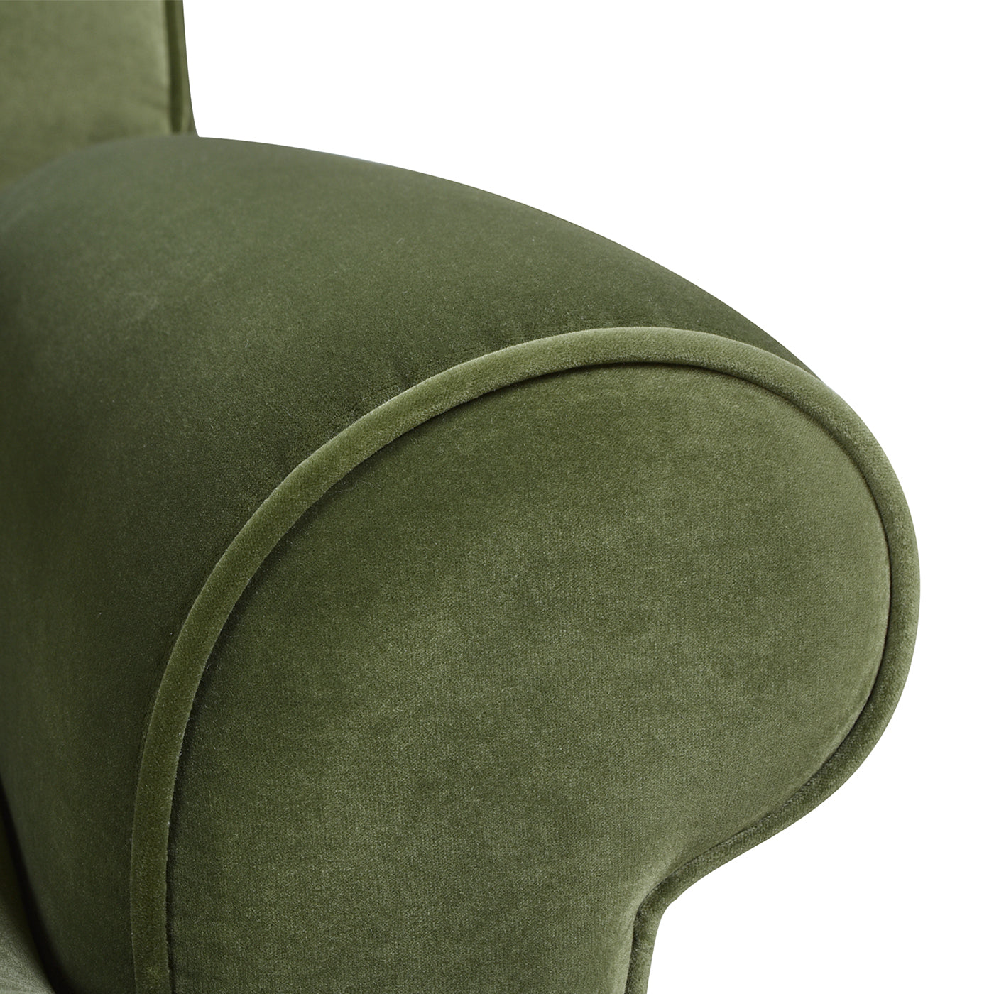 Closeup of a plush olive green velvet armchair armrest with detailed piping