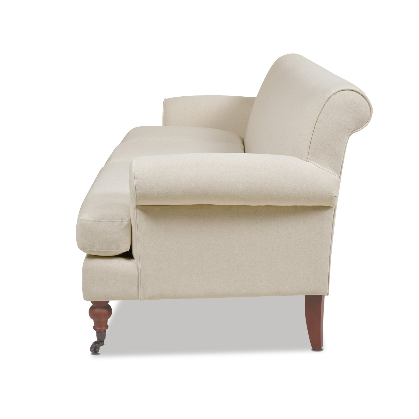 A cream fabric loveseat with rolled arms and wooden legs with casters