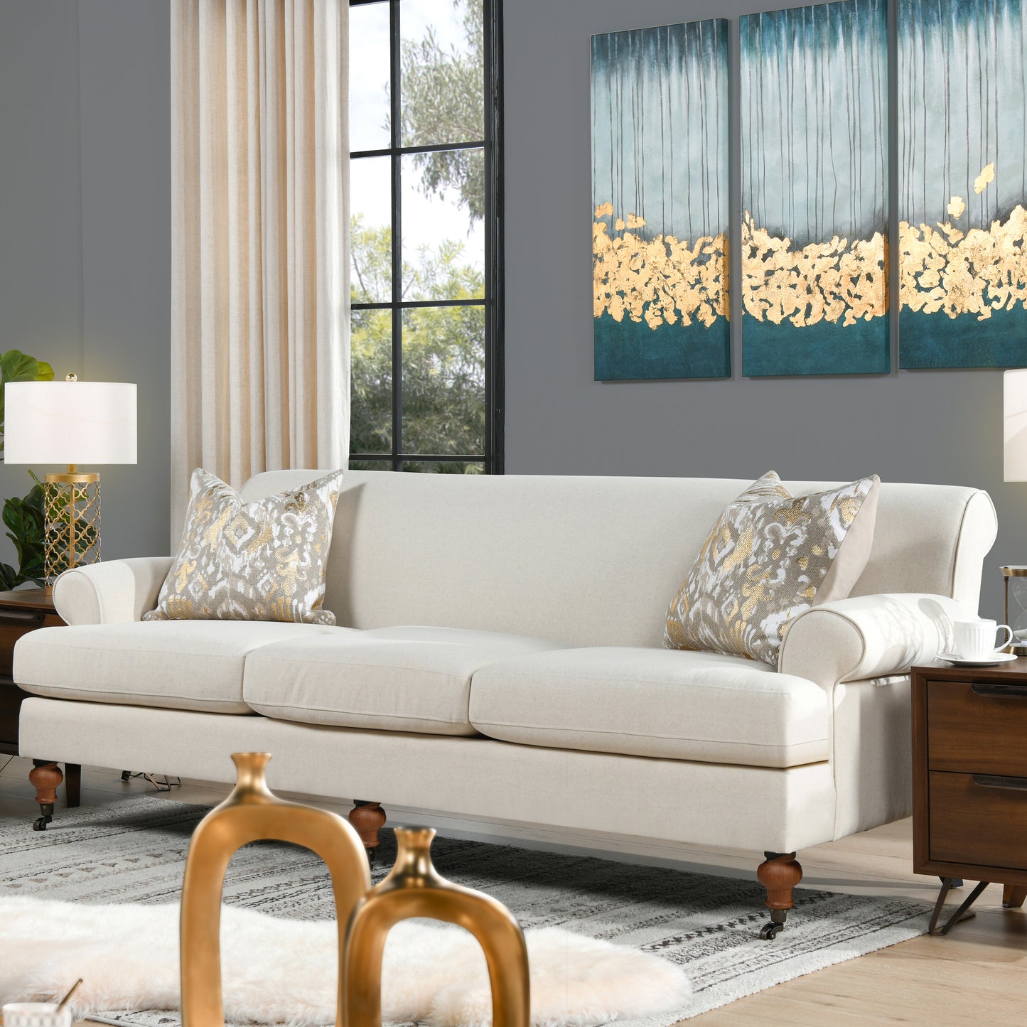 Elegant ivory linen seater sofa with carved wooden legs and decorative throw pillows