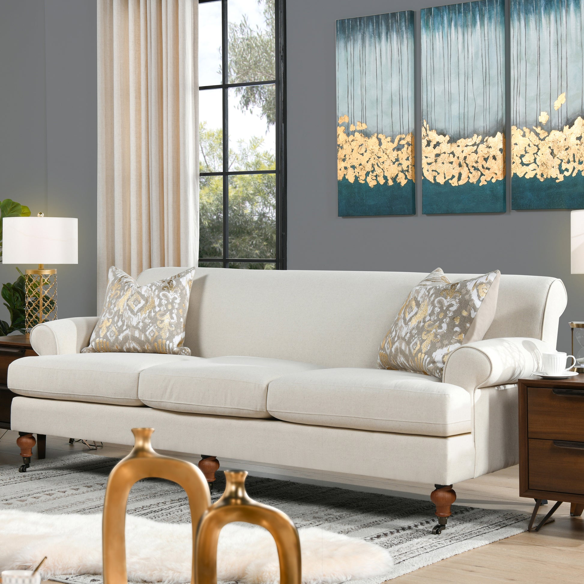 Elegant ivory linen seater sofa with carved wooden legs and decorative throw pillows