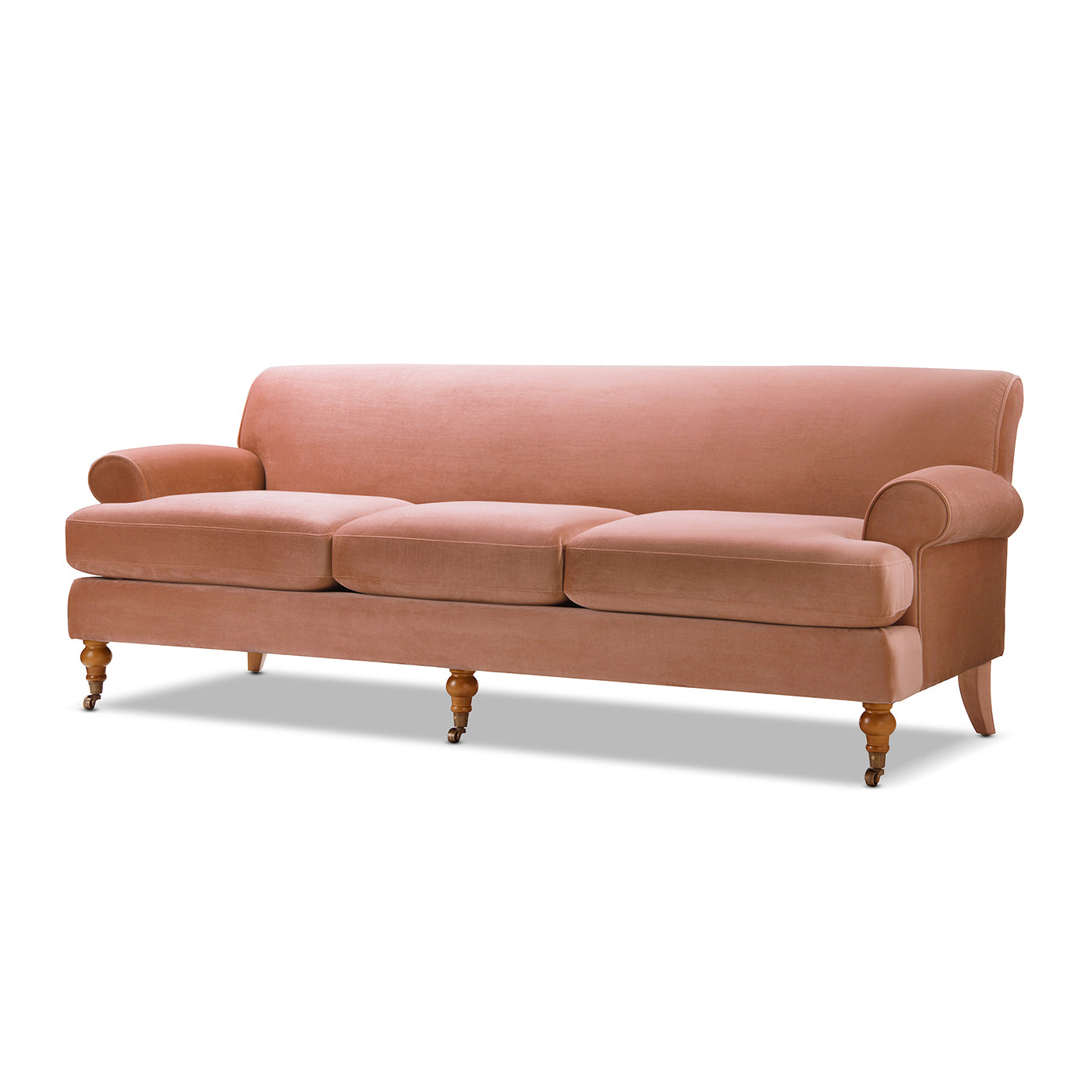 Dusty rose velvet sofa with three cushions and scrolled arms on wooden legs with casters