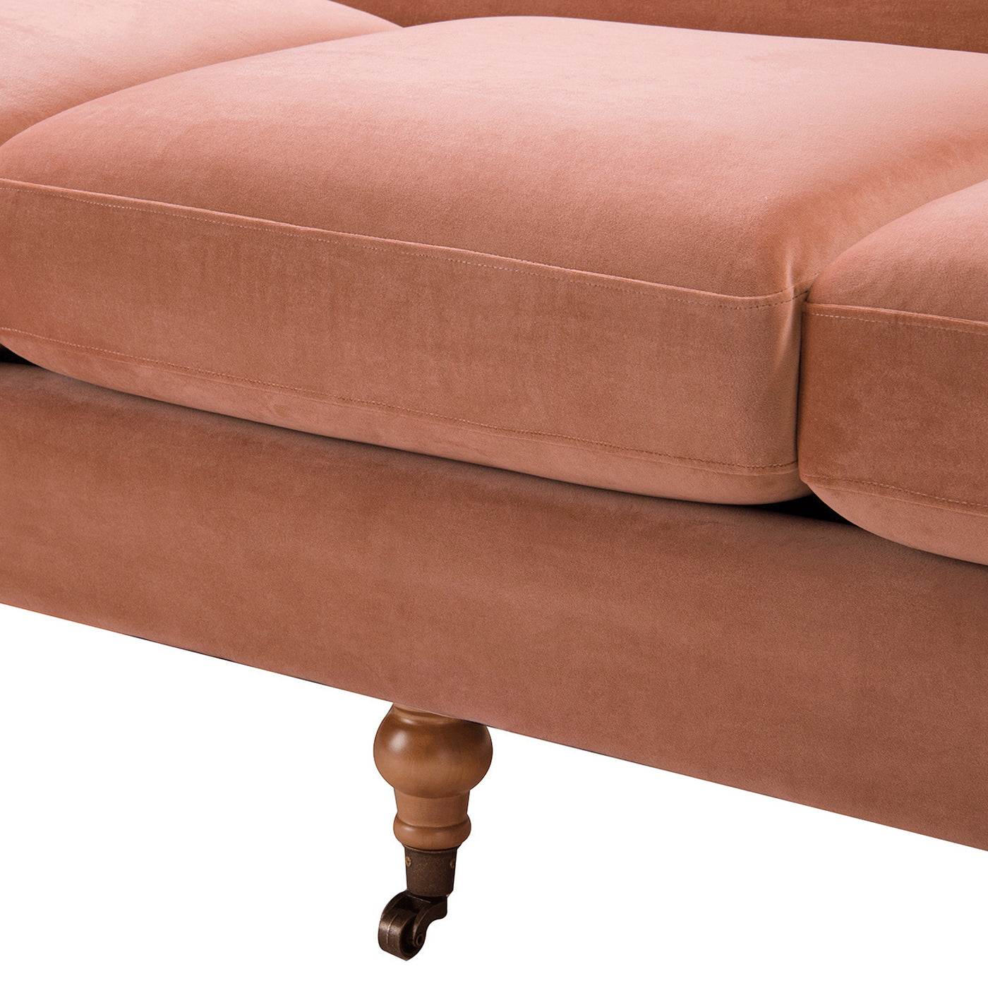 Close up of plush salmon velvet sofa seat cushions with detailed stitching and turned wooden legs