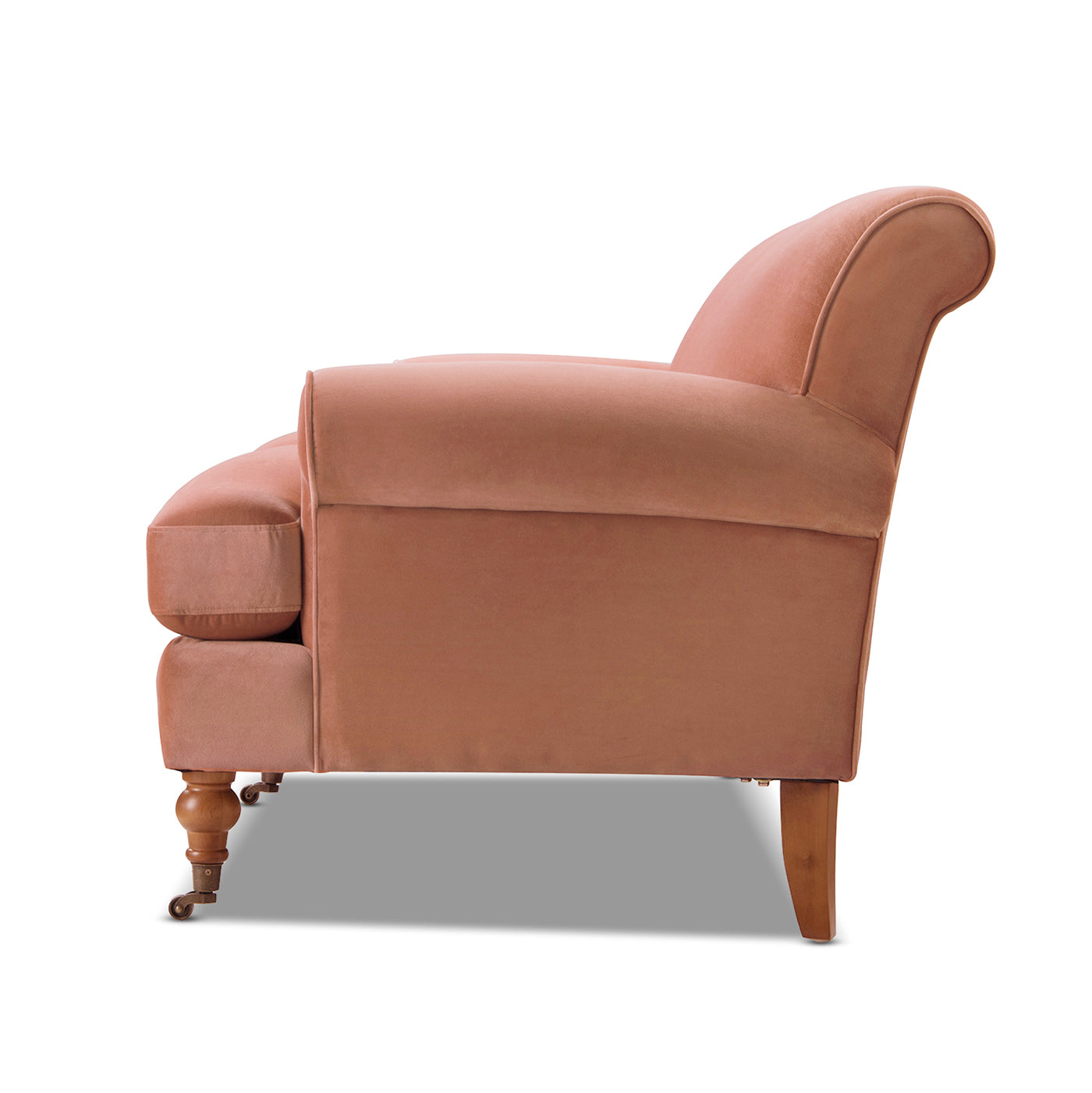Coral velvet armchair with rolled arms and wooden legs with casters