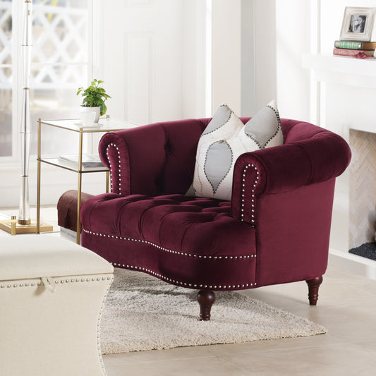 Deep red velvet tufted armchair with silver nailhead trim and plush decorative pillows