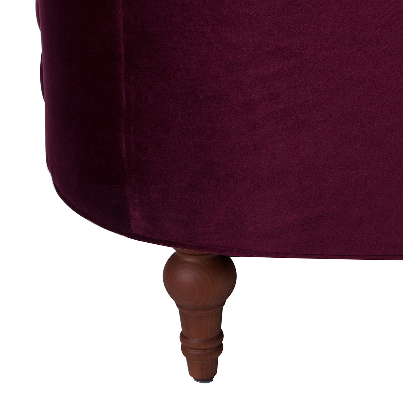 Plush plum velvet ottoman with carved wooden legs