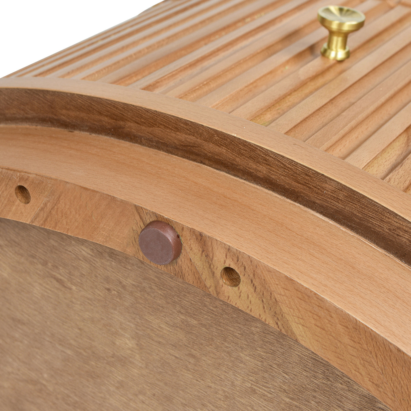 Closeup of a curved wooden bread box lid with brass knob detail