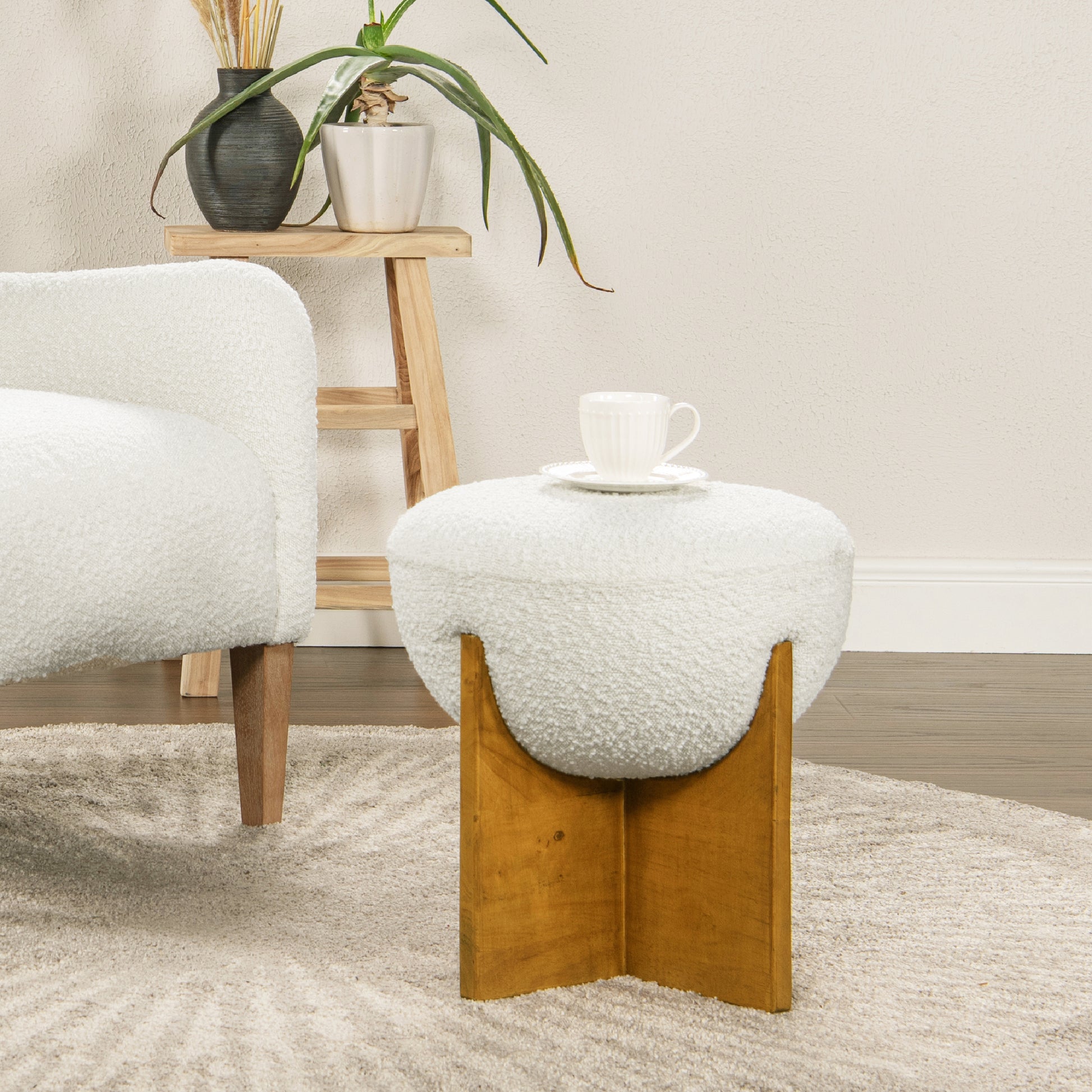 Plush white boucl ottoman with a curved wooden base and ribbed teacup on top