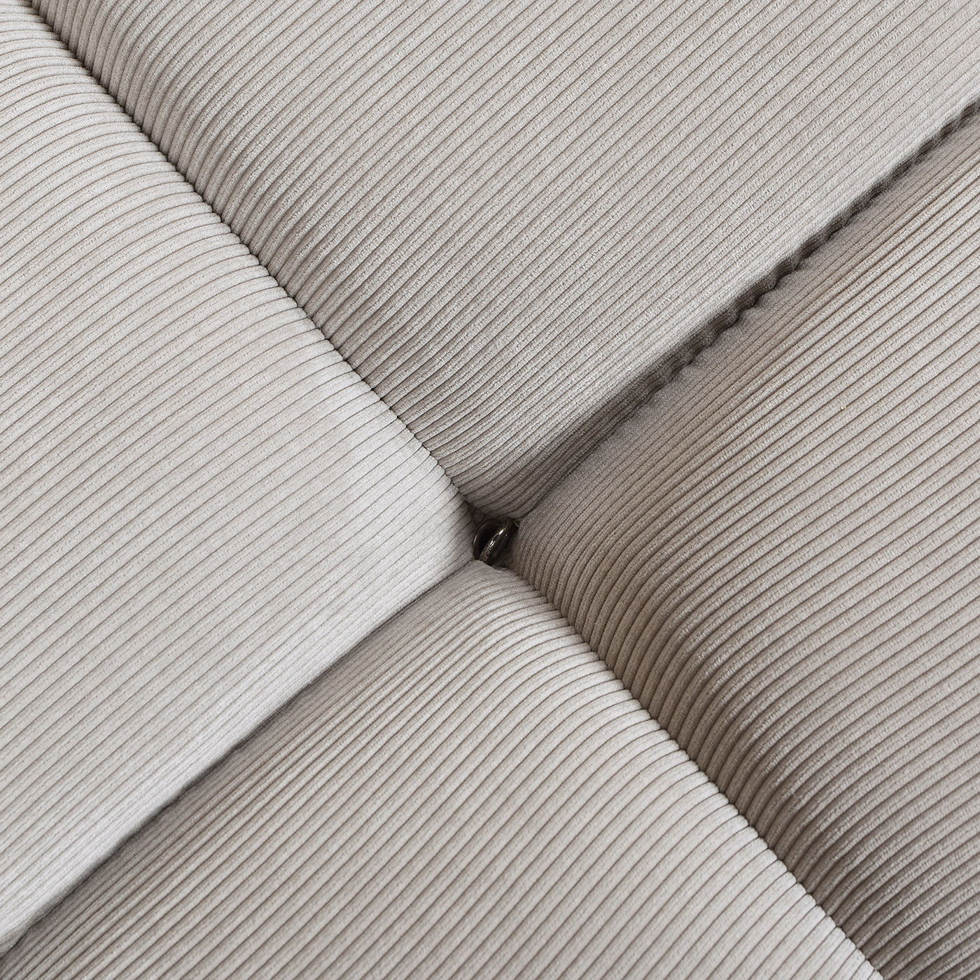 Closeup of beige corduroy fabric sofa with diamond tufting and button detail