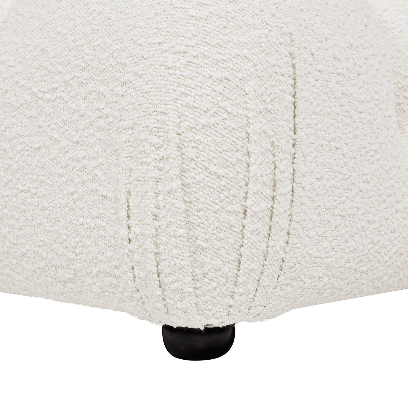 Closeup of textured cream boucle fabric on a modern armchair featuring a black cylindrical leg