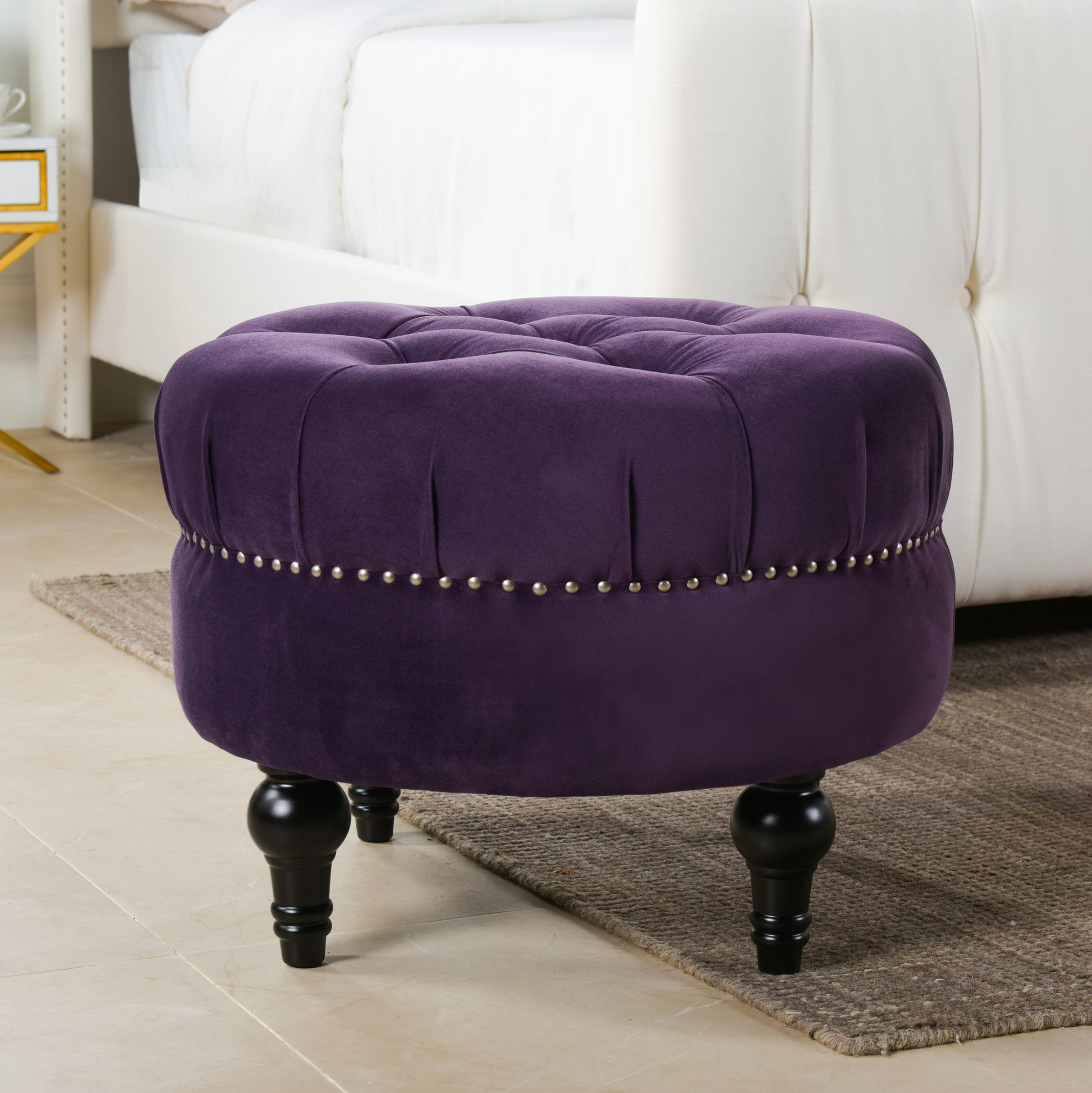 Deep purple velvet tufted ottoman with nailhead trim and turned legs