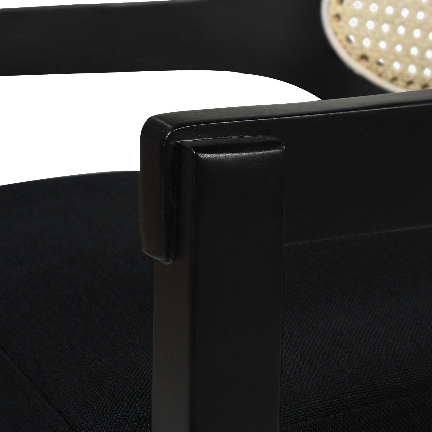 Closeup of a black upholstered dining chair armrest with a natural cane back detail