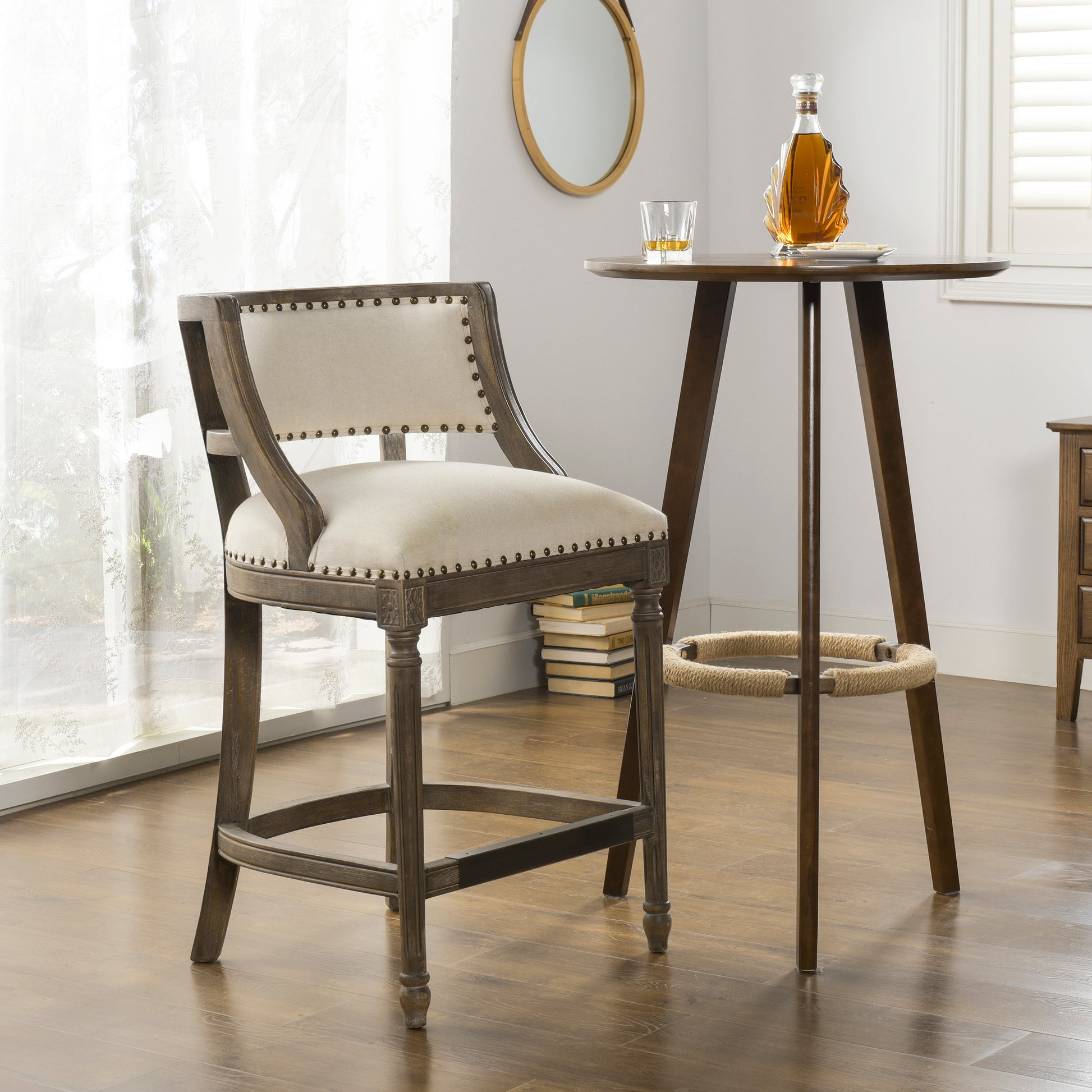 Rustic grey wooden bar stool with beige upholstered seat and nailhead trim