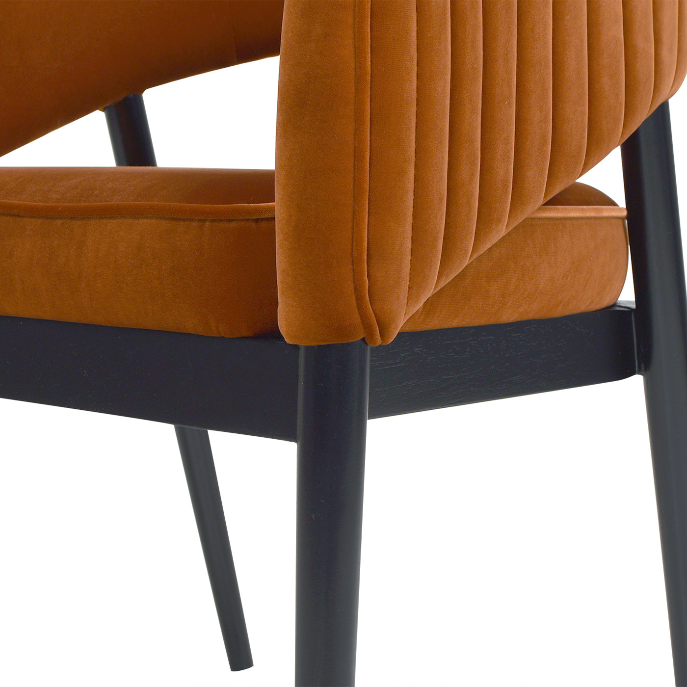 Closeup of an orange velvet armchairs ribbed backrest and seat with dark wooden legs