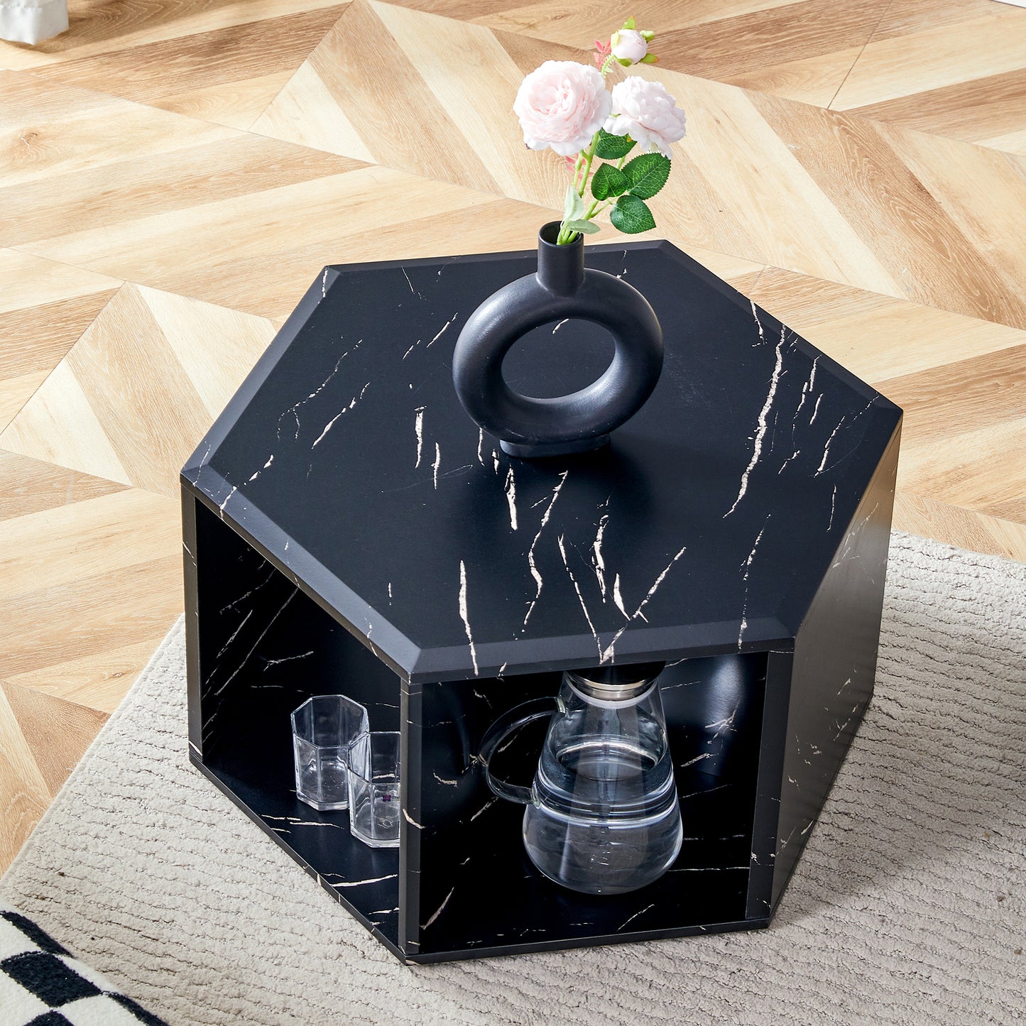 Black marble hexagonal coffee table with a circular vase holding pink flowers