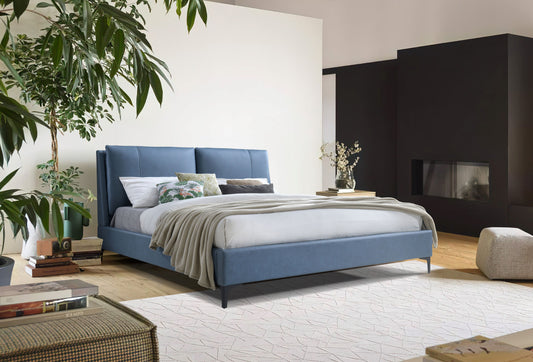 Modern blue upholstered king size bed with tufted headboard and plush bedding
