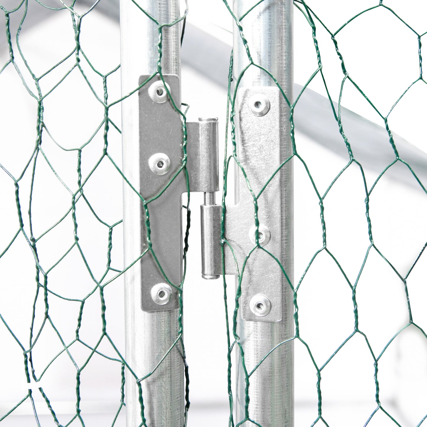Closeup of a galvanized steel gate hinge connecting two vertical posts with green wire mesh visible