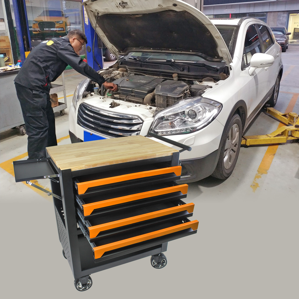 Black rolling tool chest with five orange drawers and a wooden top next to a white car