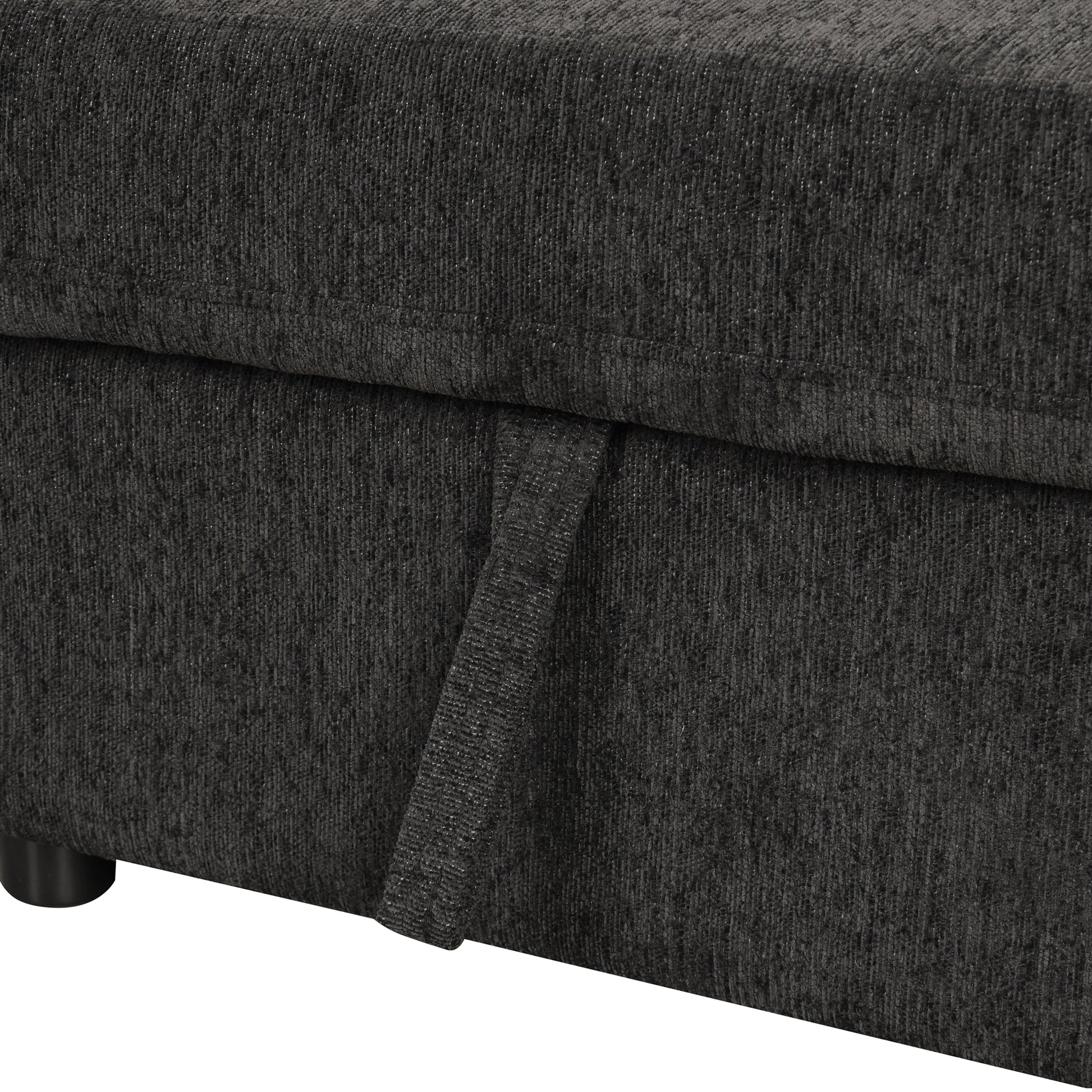 Closeup of dark gray textured fabric on a couch with a pull tab