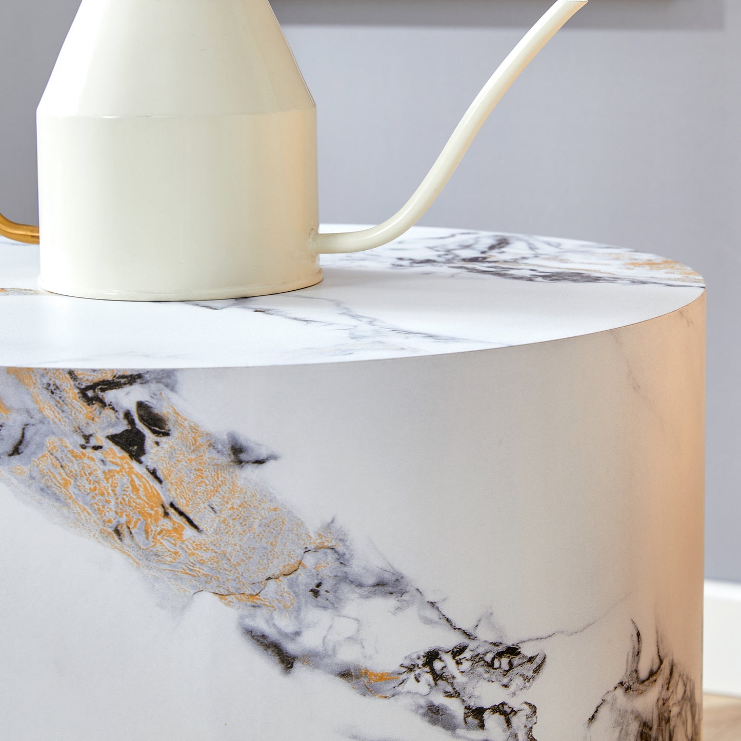 Cream watering can with gold handle on a marble side table