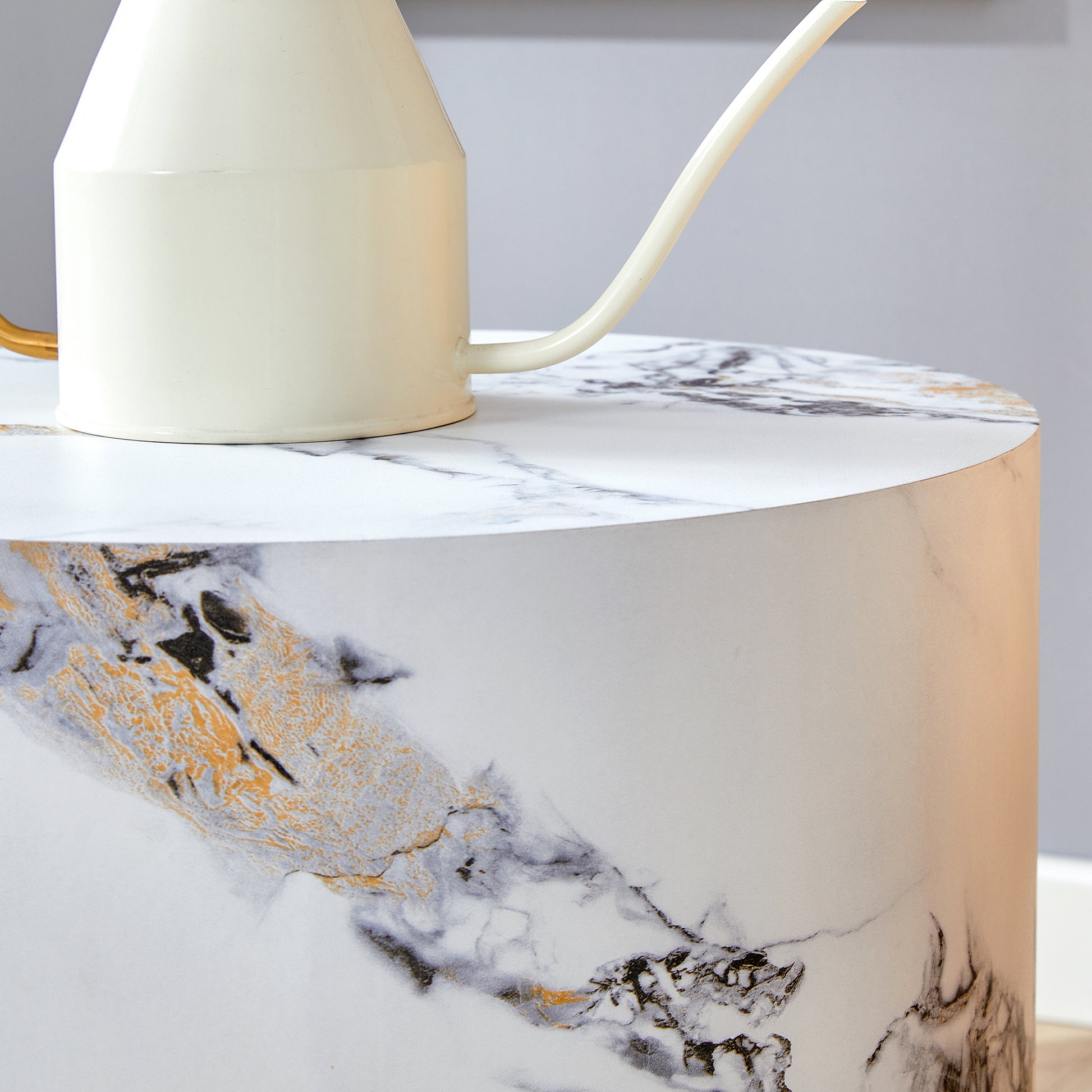 Cream watering can with gold handle on a marble side table