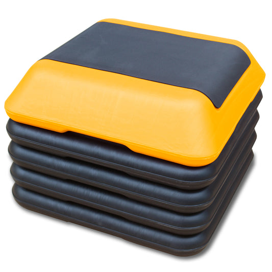 Stack of yellow and black adjustable aerobic step platforms for home workouts
