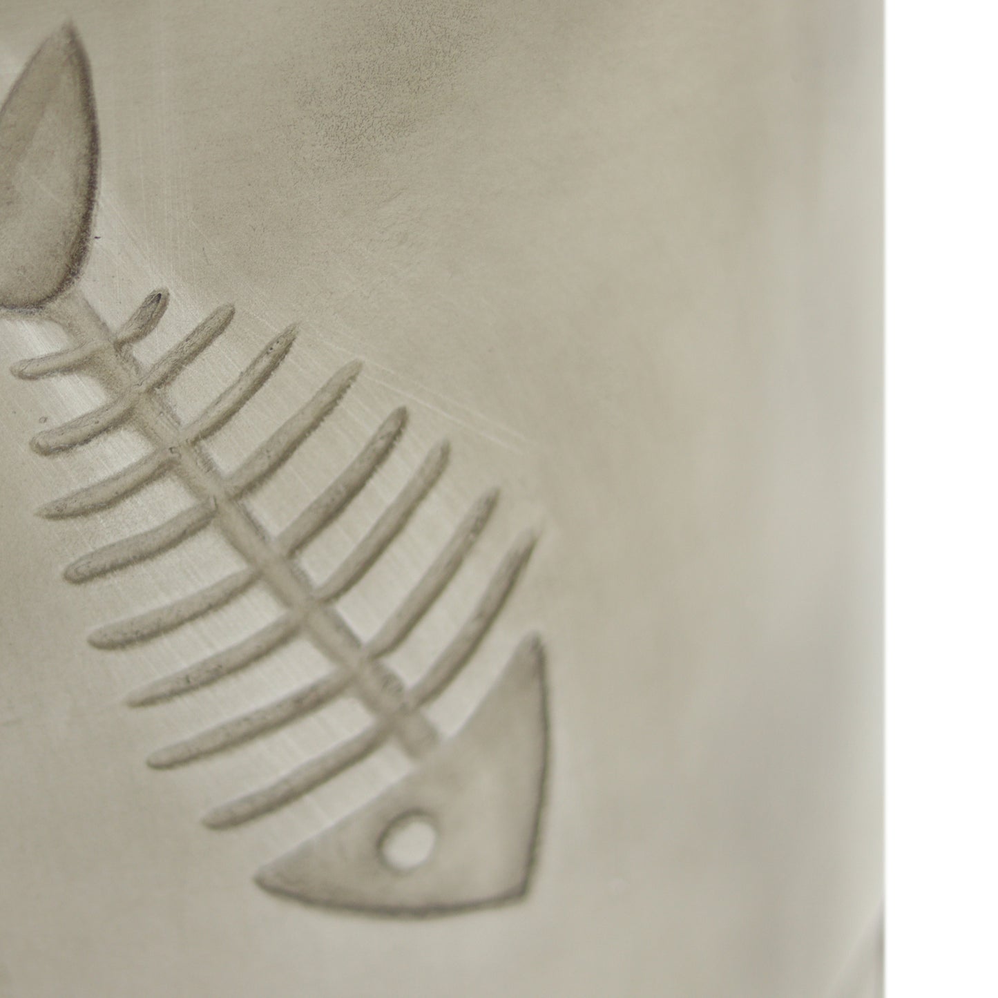 Etched fish bone pattern on a textured ceramic mug perfect for coffee lovers