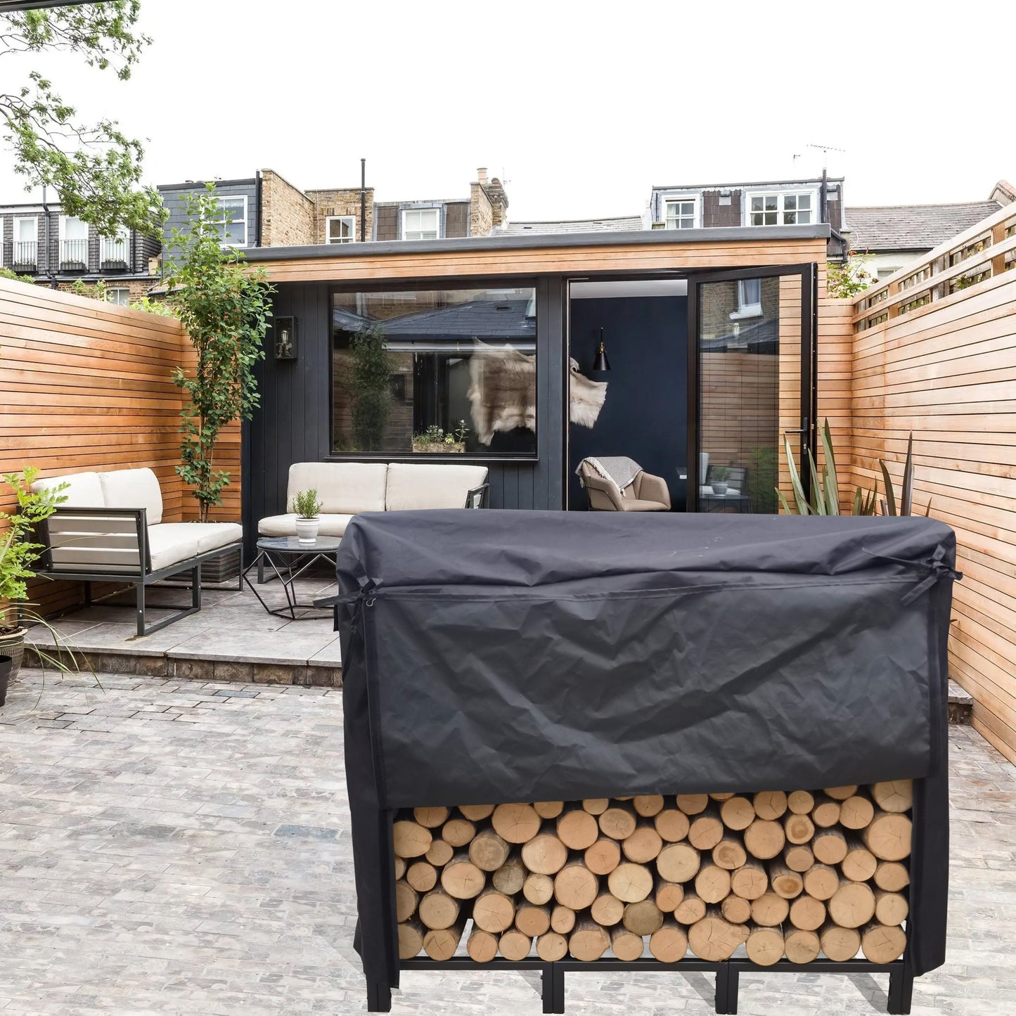 Black waterproof log store cover protecting stacked firewood in a garden setting