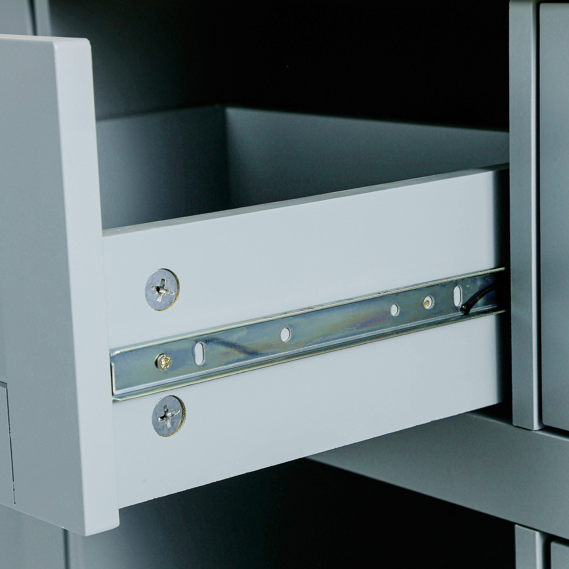 Closeup of a grey drawer with metal runner and visible screw