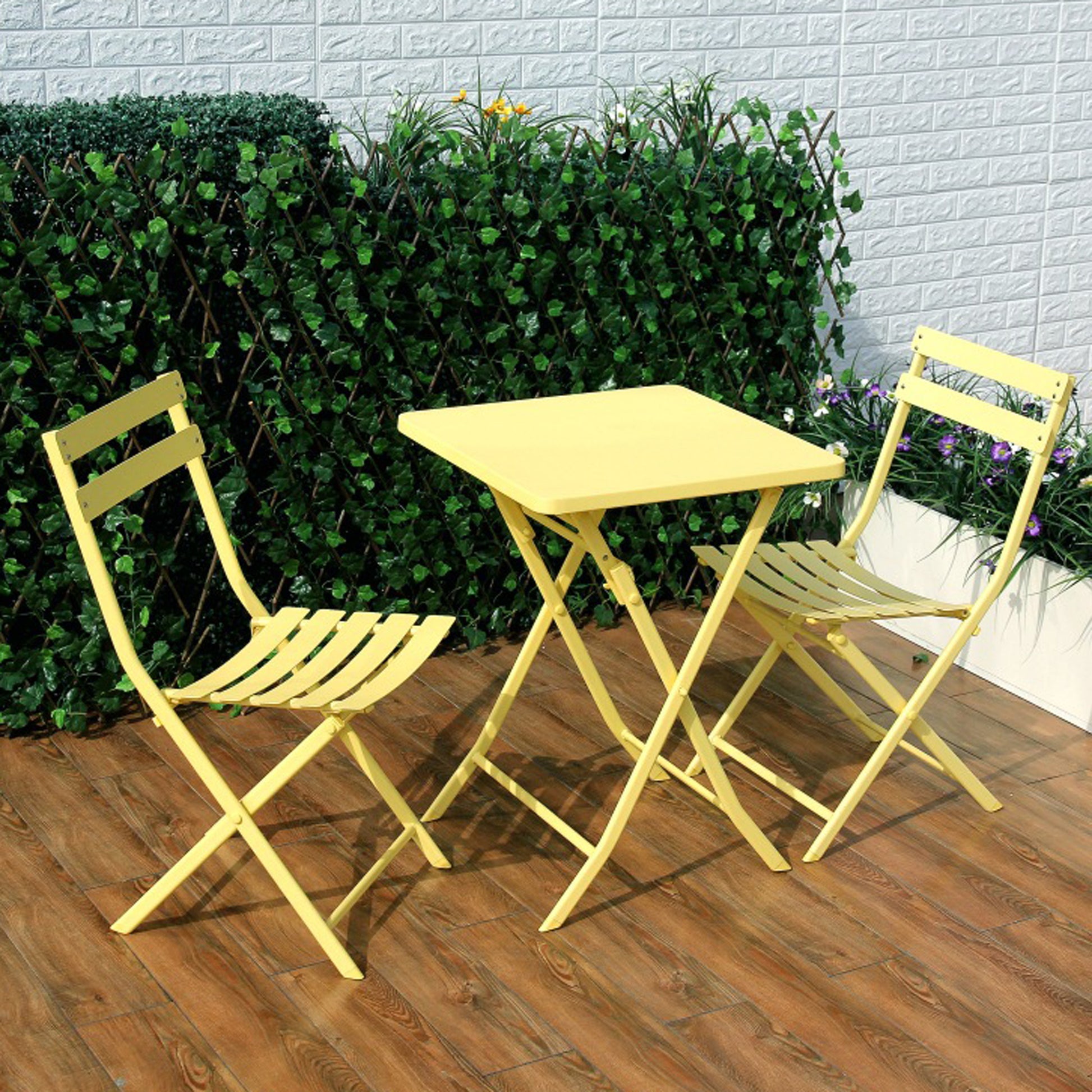 Yellow metal folding bistro set with square table and two chairs on a patio