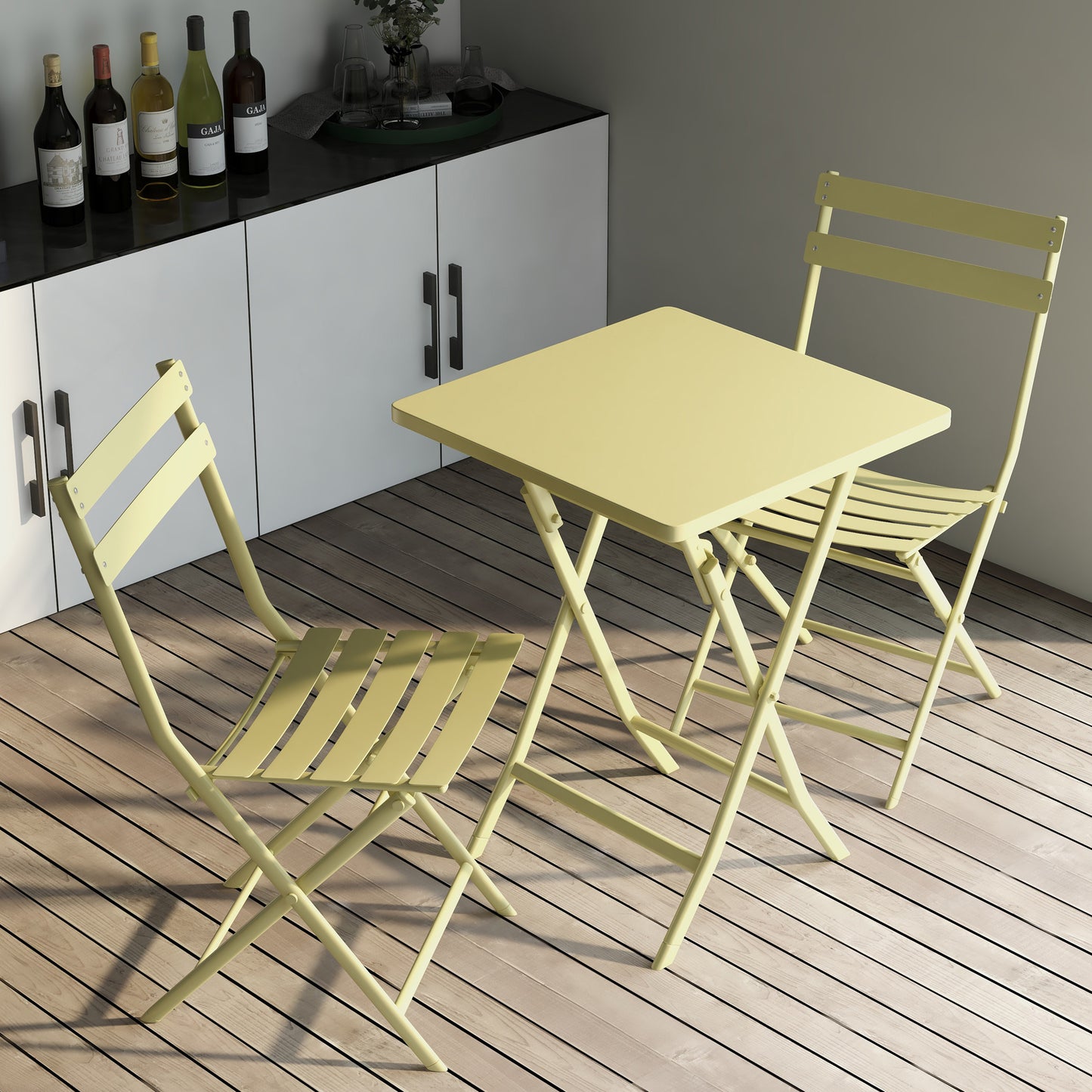 Pale yellow metal bistro set with folding table and two chairs on wooden deck