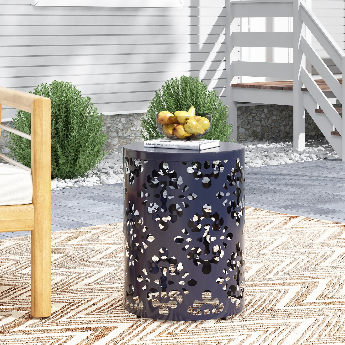 Dark navy metal outdoor side table with intricate floral cutouts on a patio