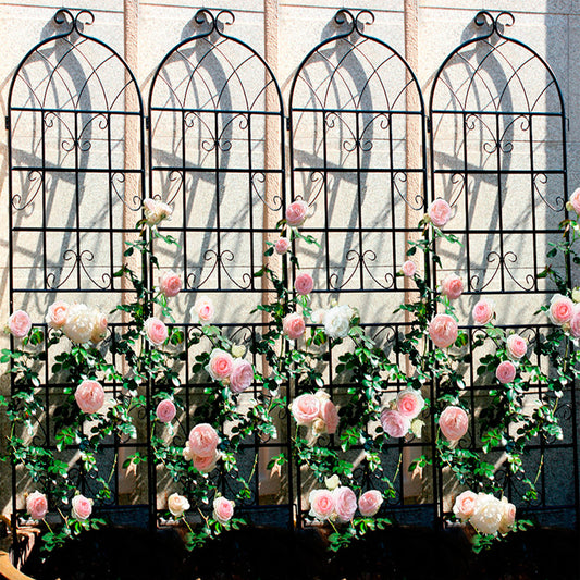 Four black wrought iron garden trellis panels with climbing pink roses