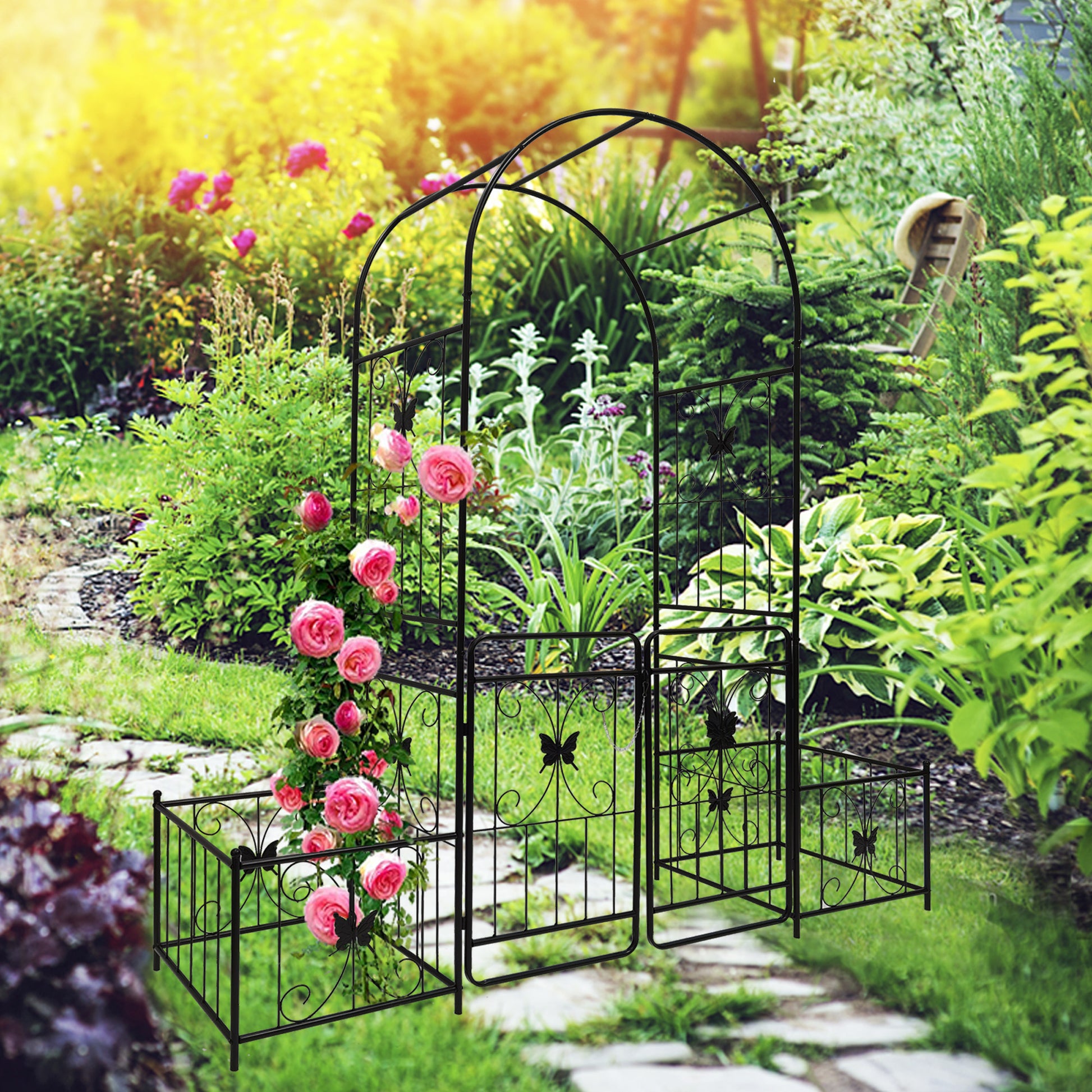 Black metal garden arch with butterfly accents supporting climbing pink roses