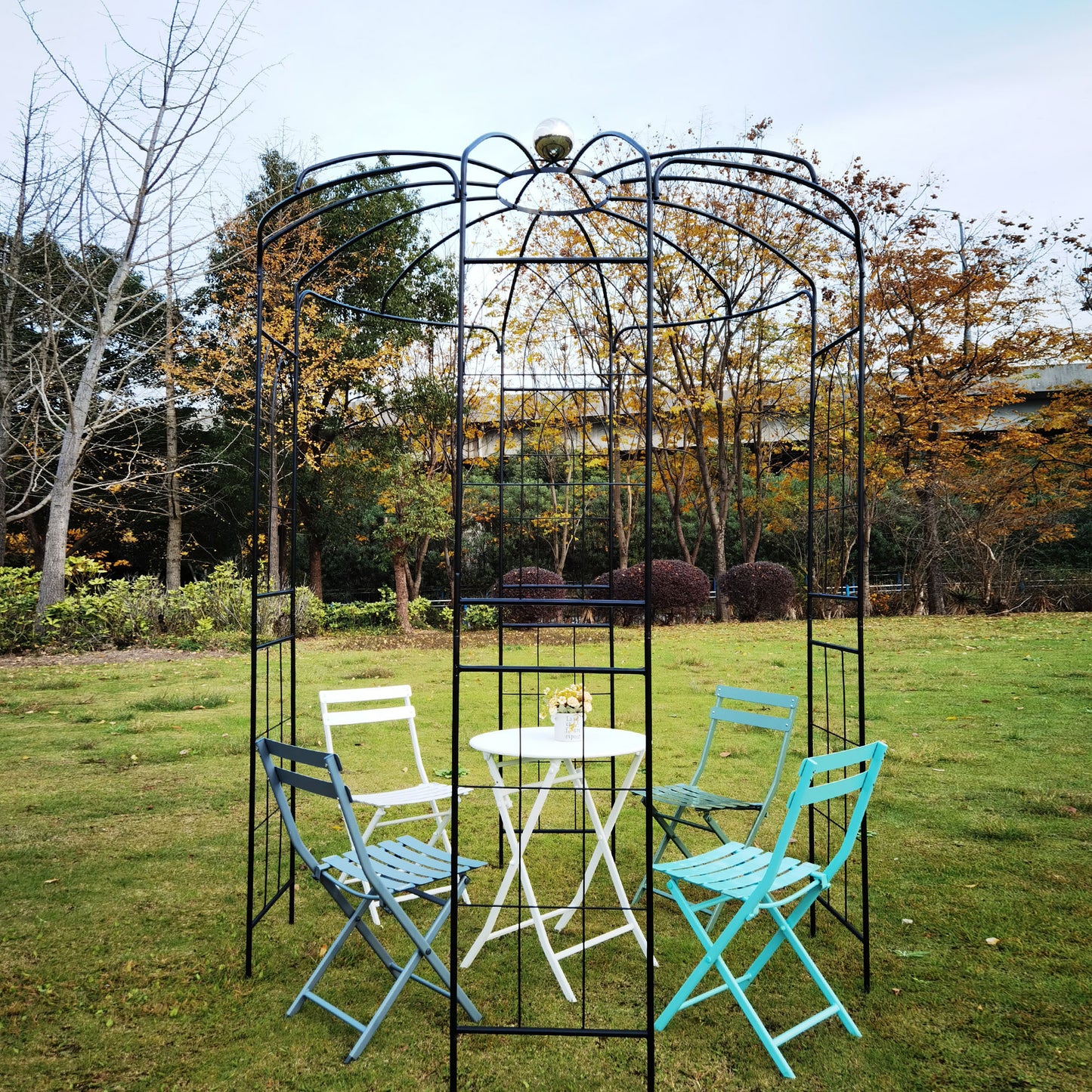 Black metal garden arbor with white table and blue chairs