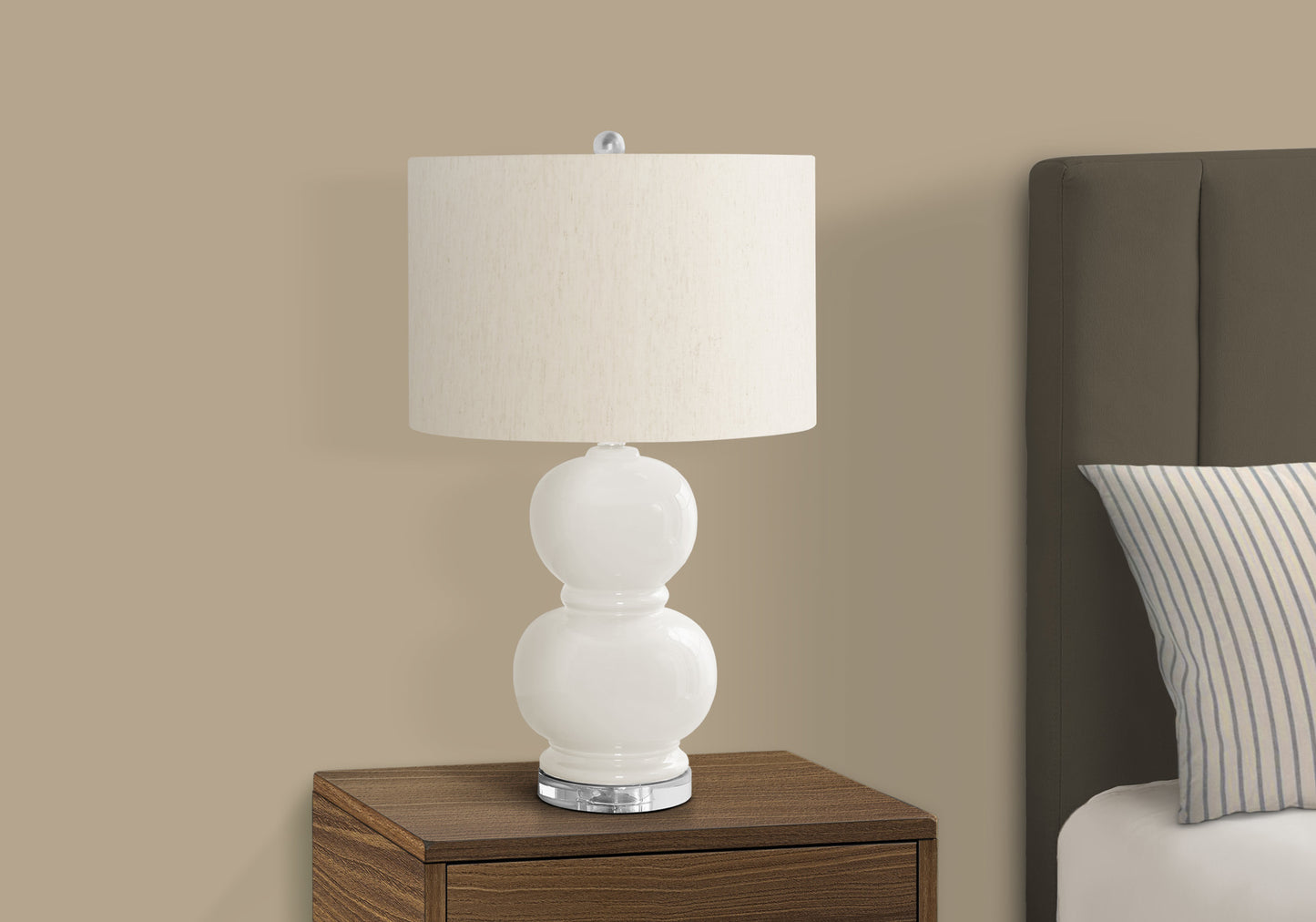 White ceramic table lamp with offwhite linen shade on a dark wood nightstand