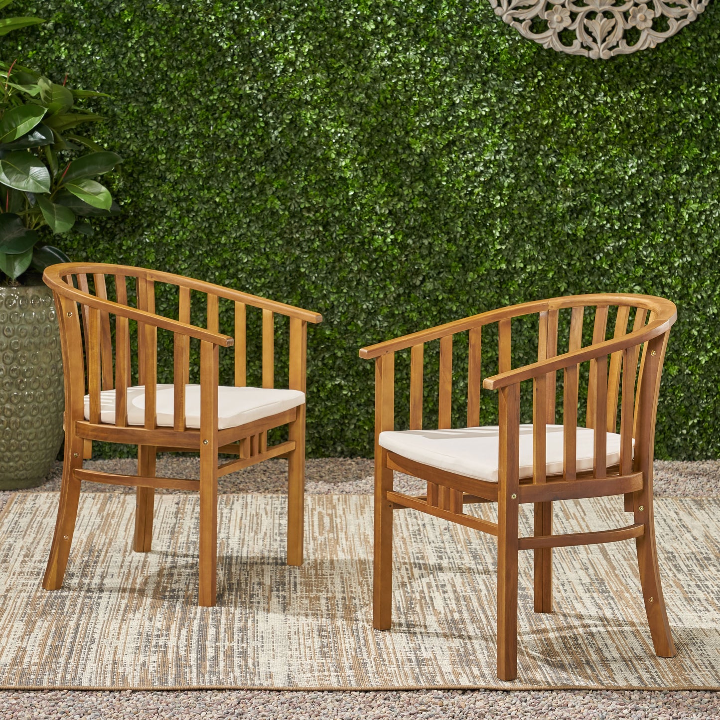 Two natural wood outdoor chairs with cream cushions on a patterned rug