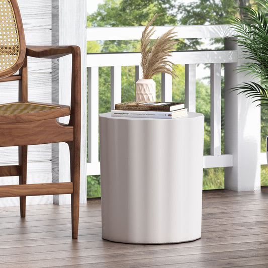 Textured white cylinder accent table with stacked books and pampas grass