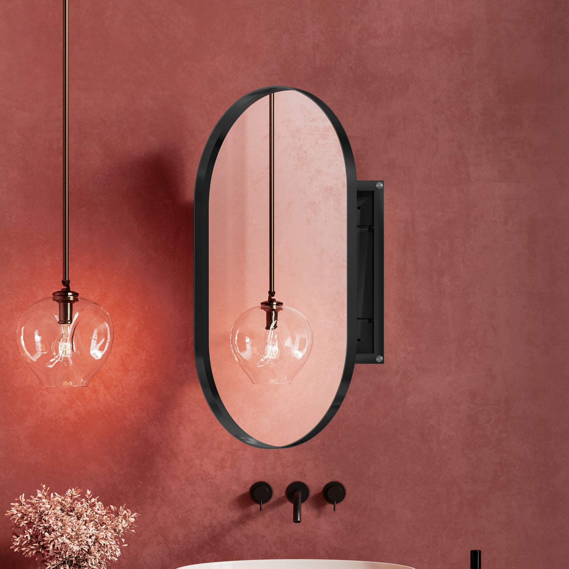 Oval black framed bathroom mirror with copper accents reflecting a pendant light
