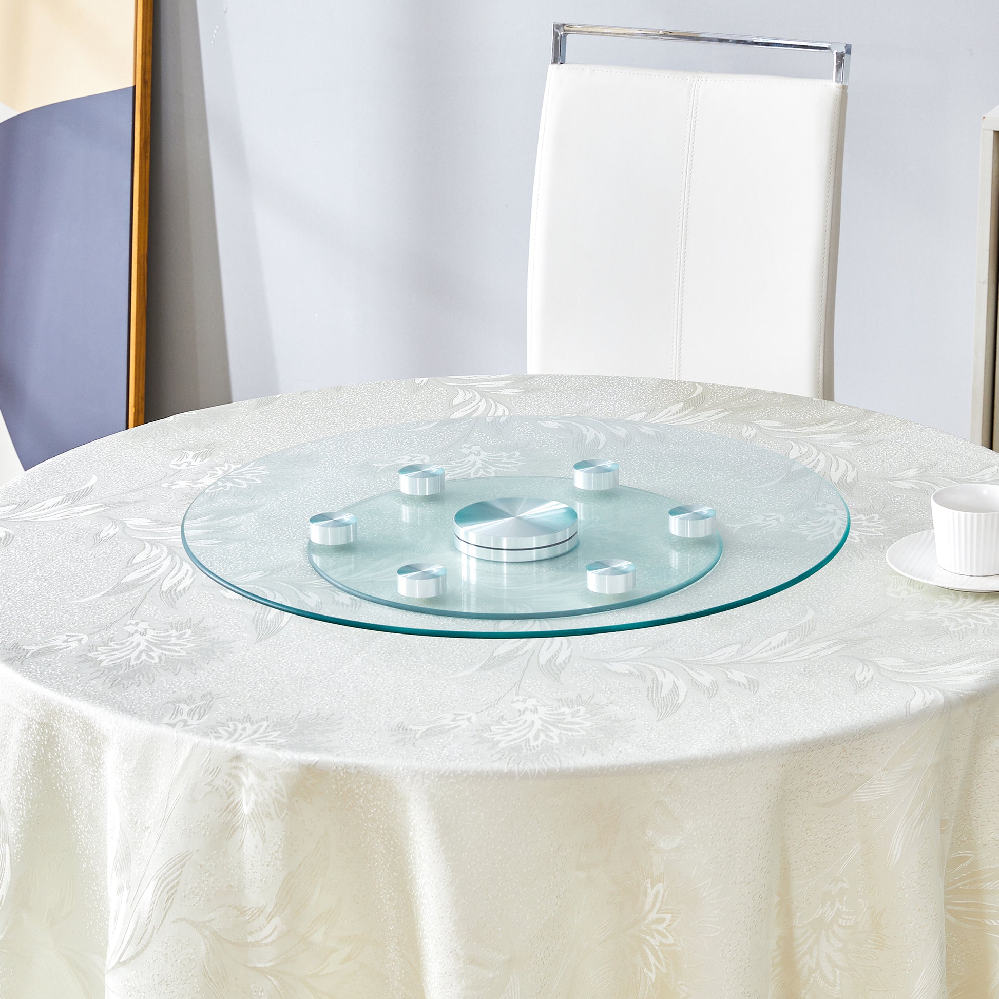 Clear glass lazy Susan with silver accents on a patterned tablecloth