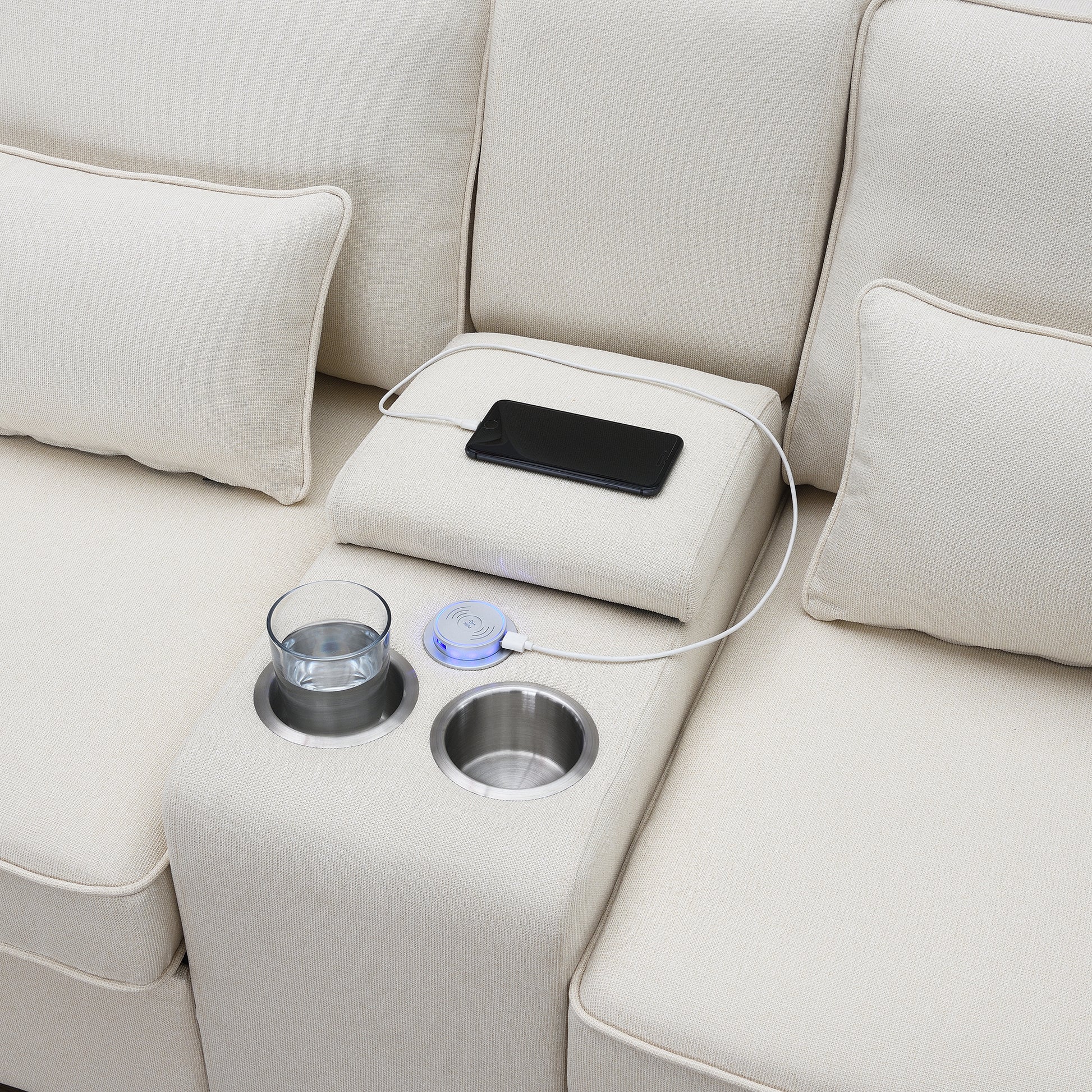 Close up of modern sofa armrest with builtin wireless phone charger and cup holders
