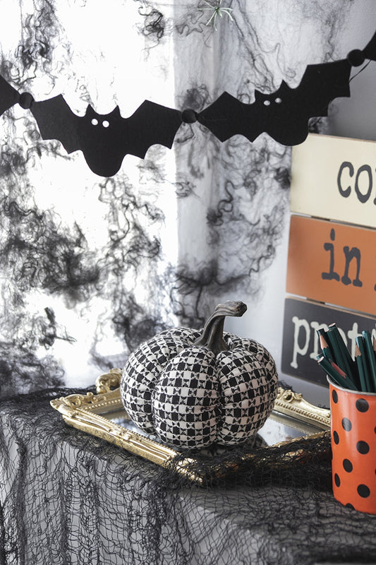 Black and white checkered fabric pumpkin with realistic stem on gold tray
