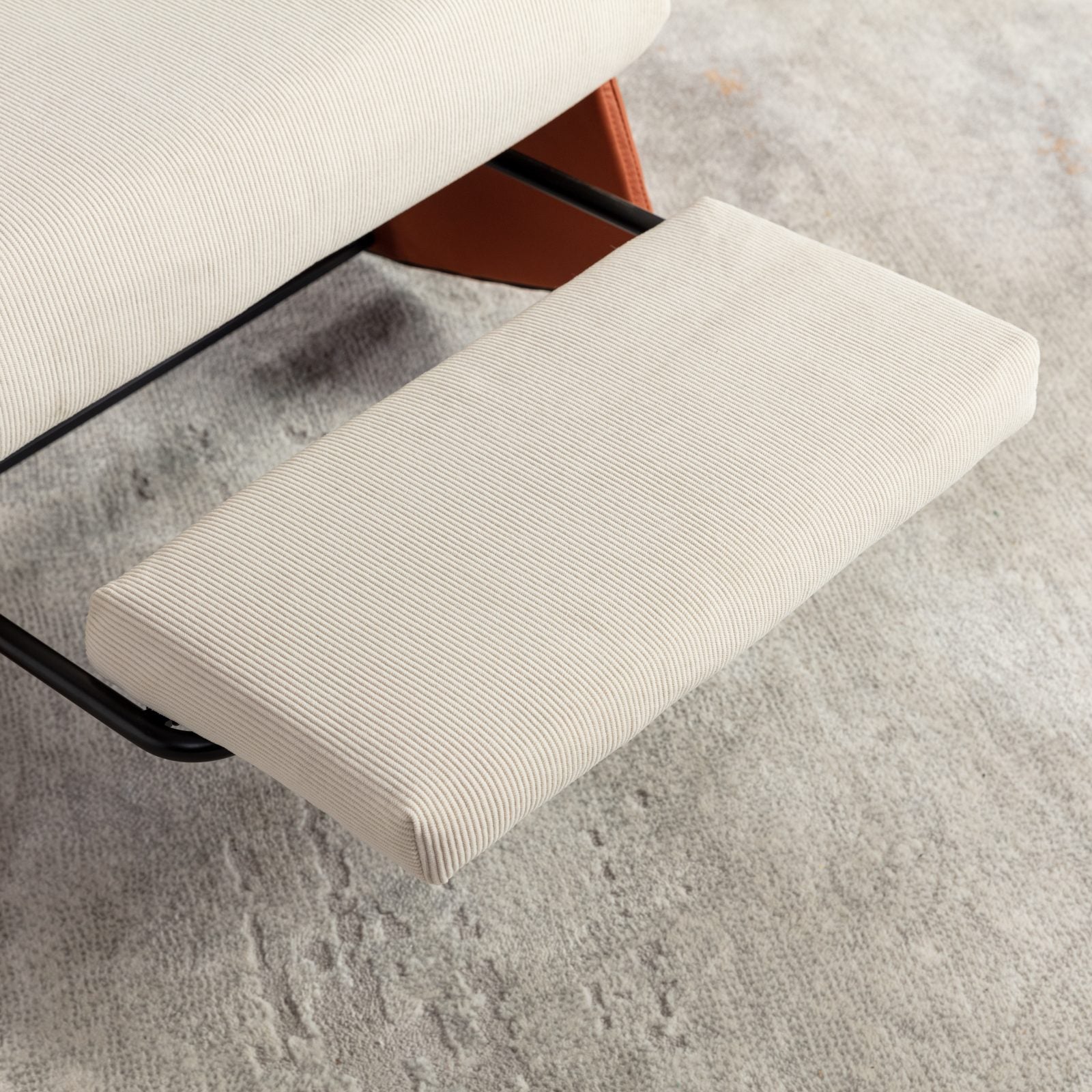 Closeup of a modern corduroy ottoman in a neutral cream color complementing a grey textured rug
