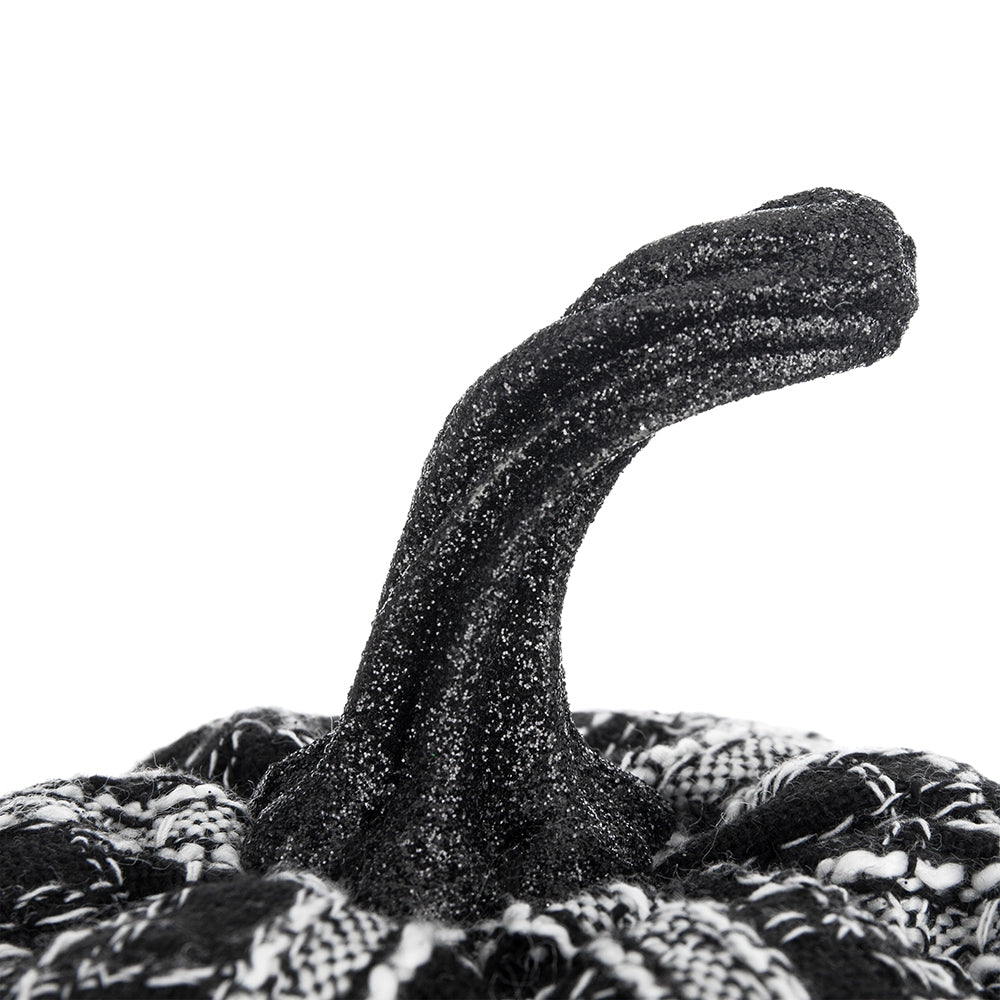 Close up of a black glitter pumpkin stem on a patterned fabric gourd